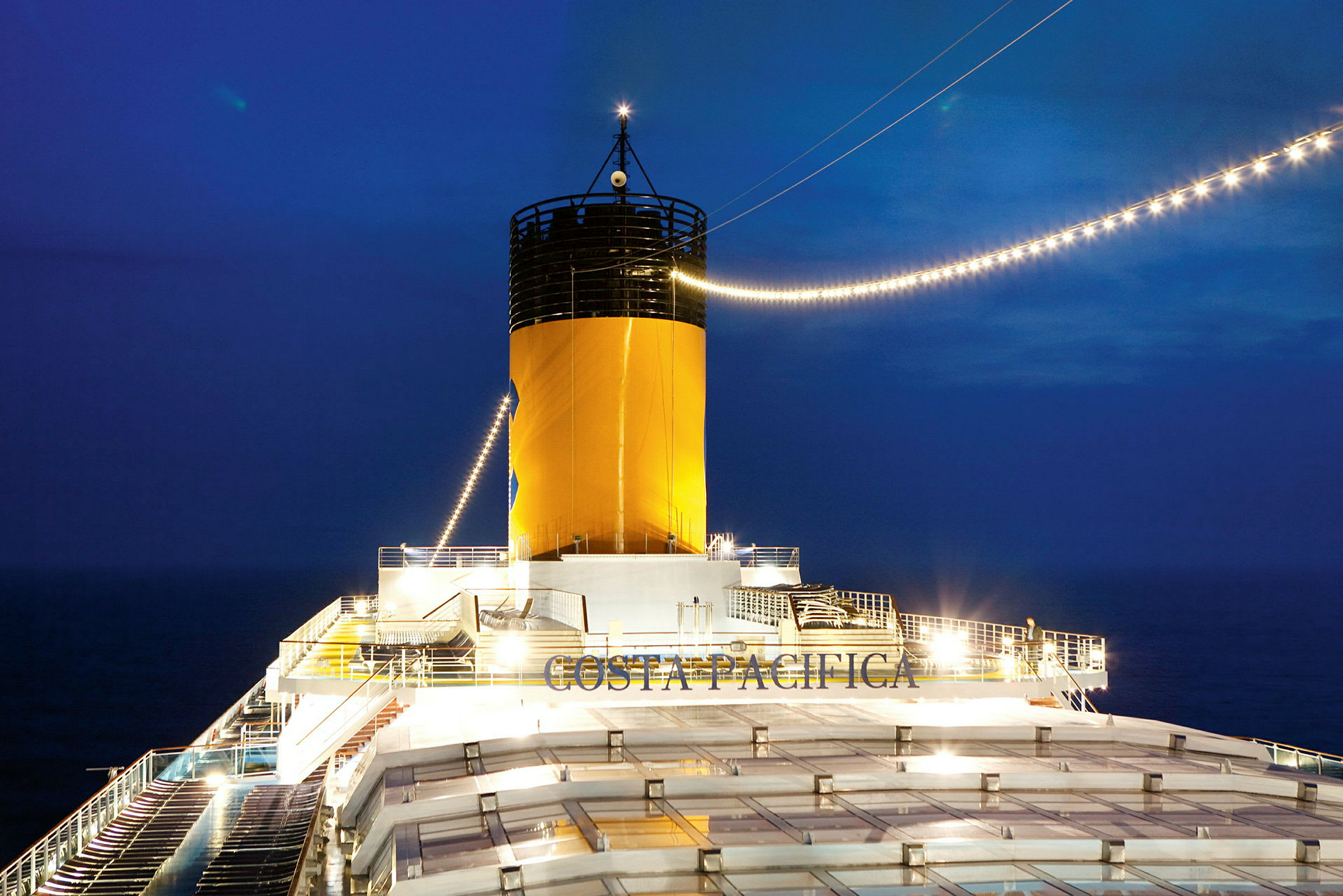 Billede af en skorsten på et krydstogtskib med teksten 'Costa Pacifica' synlig om natten. (AI-genereret tekst)