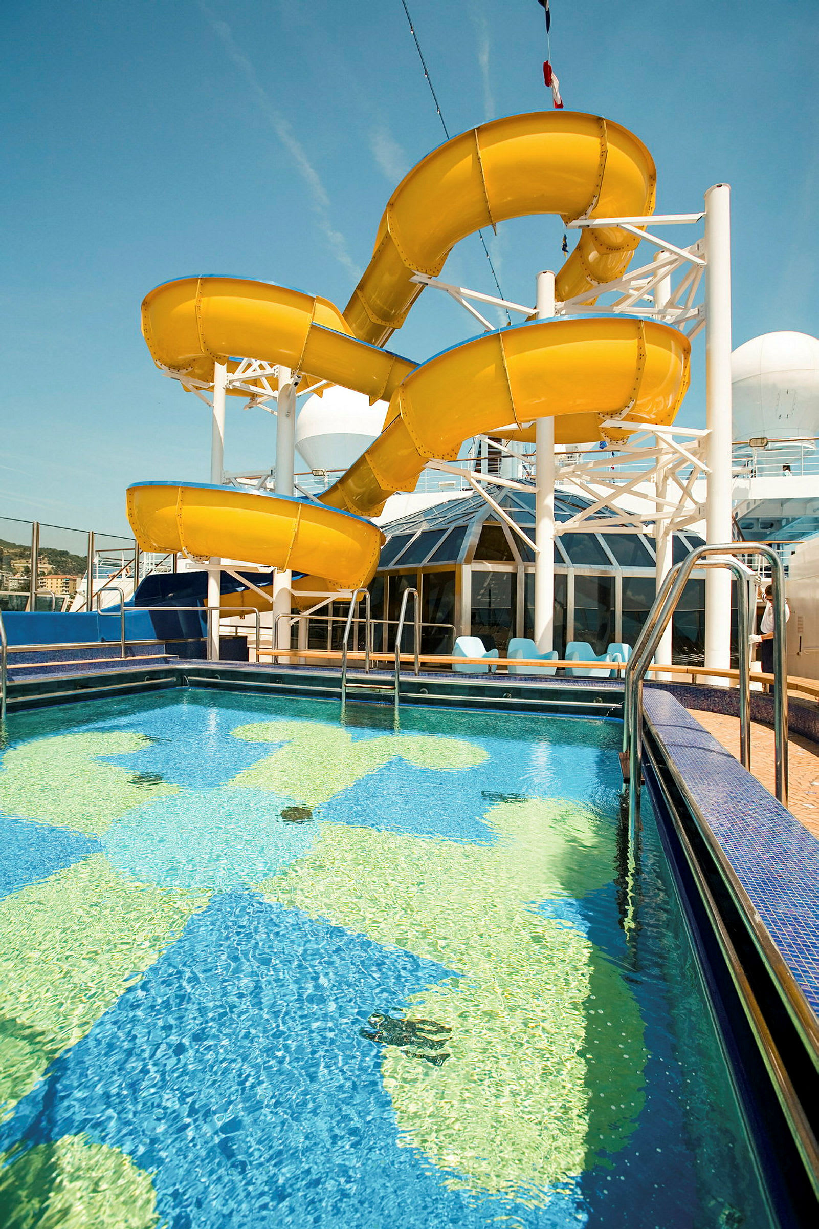 Swimmingpool med en gul vandrutschebane i baggrunden. (AI-genereret tekst)