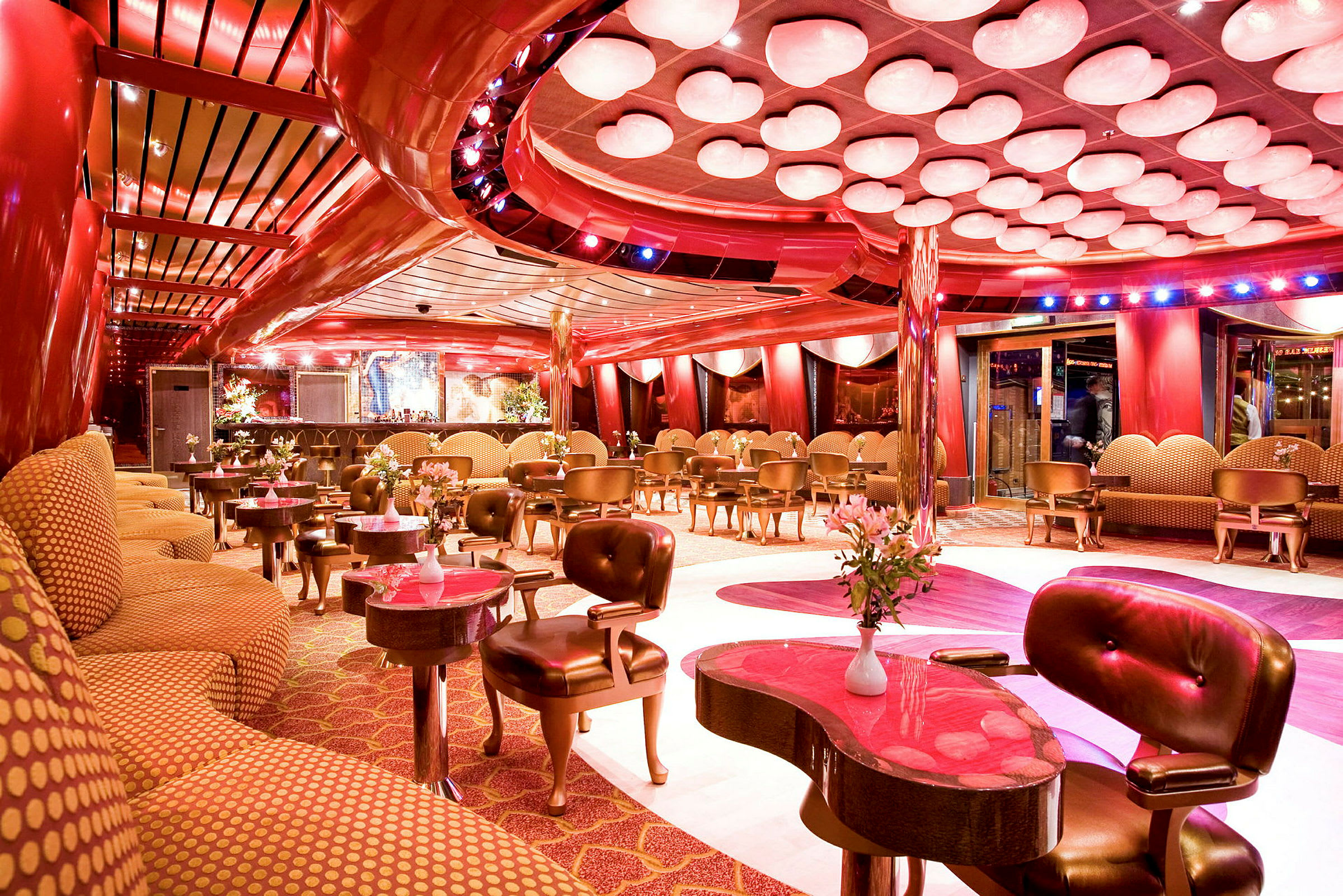 En elegant lounge med røde og gulddetaljer, moderne indretning og blomsterdekorationer. (AI-genereret tekst)