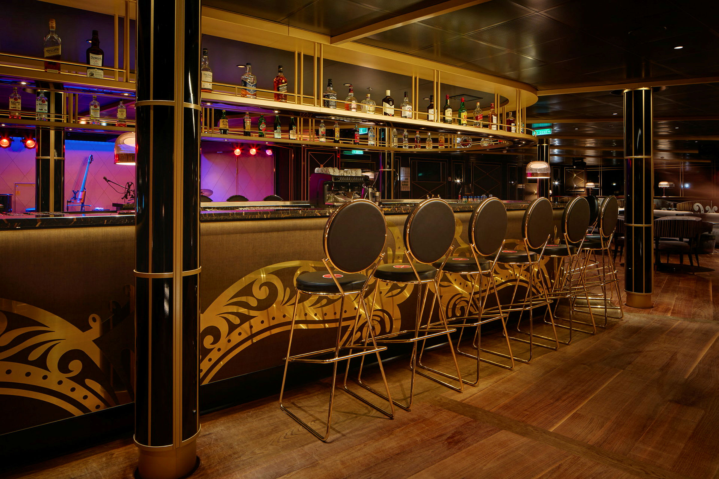 En elegant bar med høje stole og en hylde med flasker over bardisken. Interiøret har gyldne dekorationer. (AI-genereret tekst)