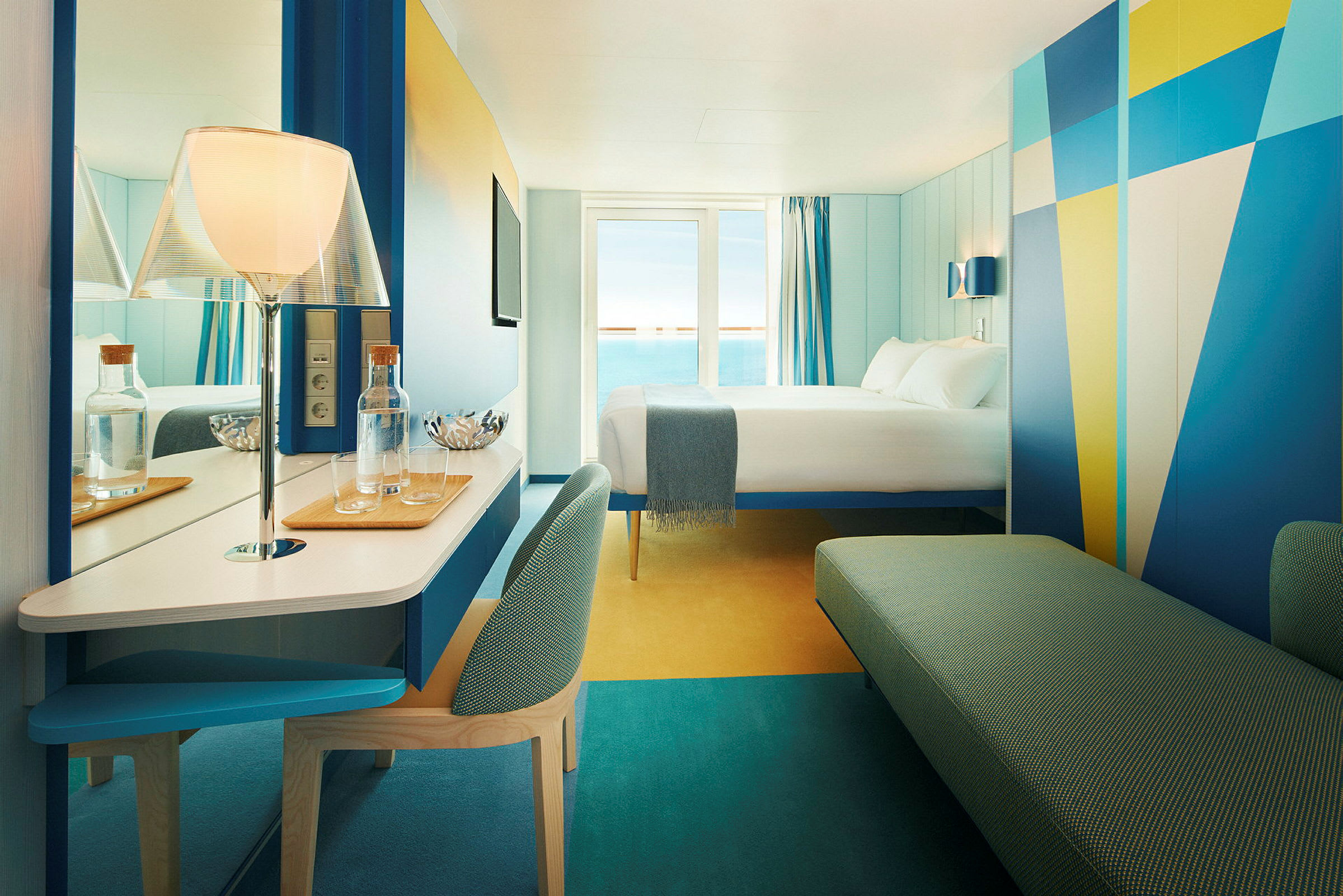Hotelværelse med moderne design og havudsigt. En seng er placeret mod et vindue med blå gardiner. (AI-genereret tekst)
