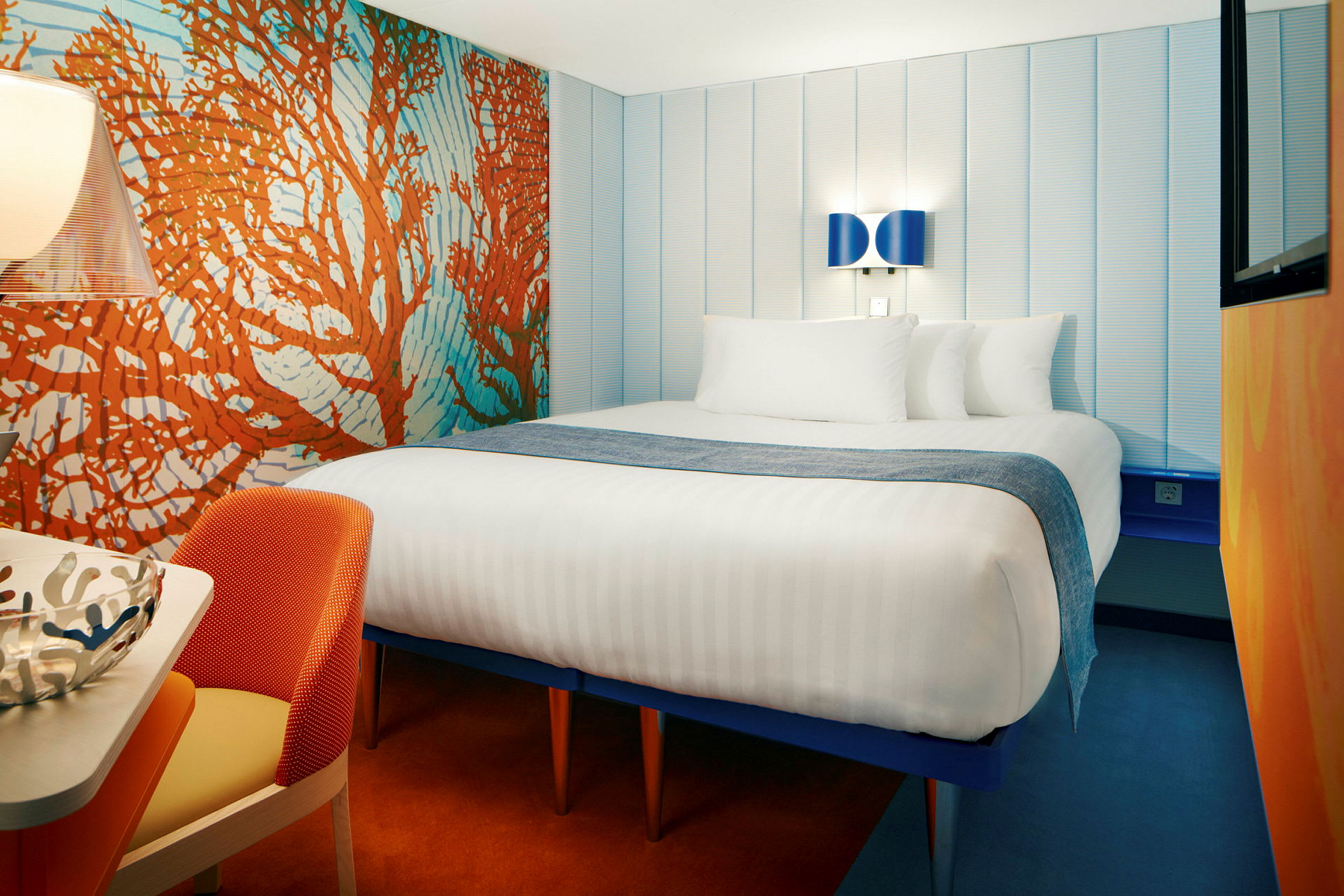 Hotelværelse med en stor seng, farverigt interiør og moderne belysning. (AI-genereret tekst)