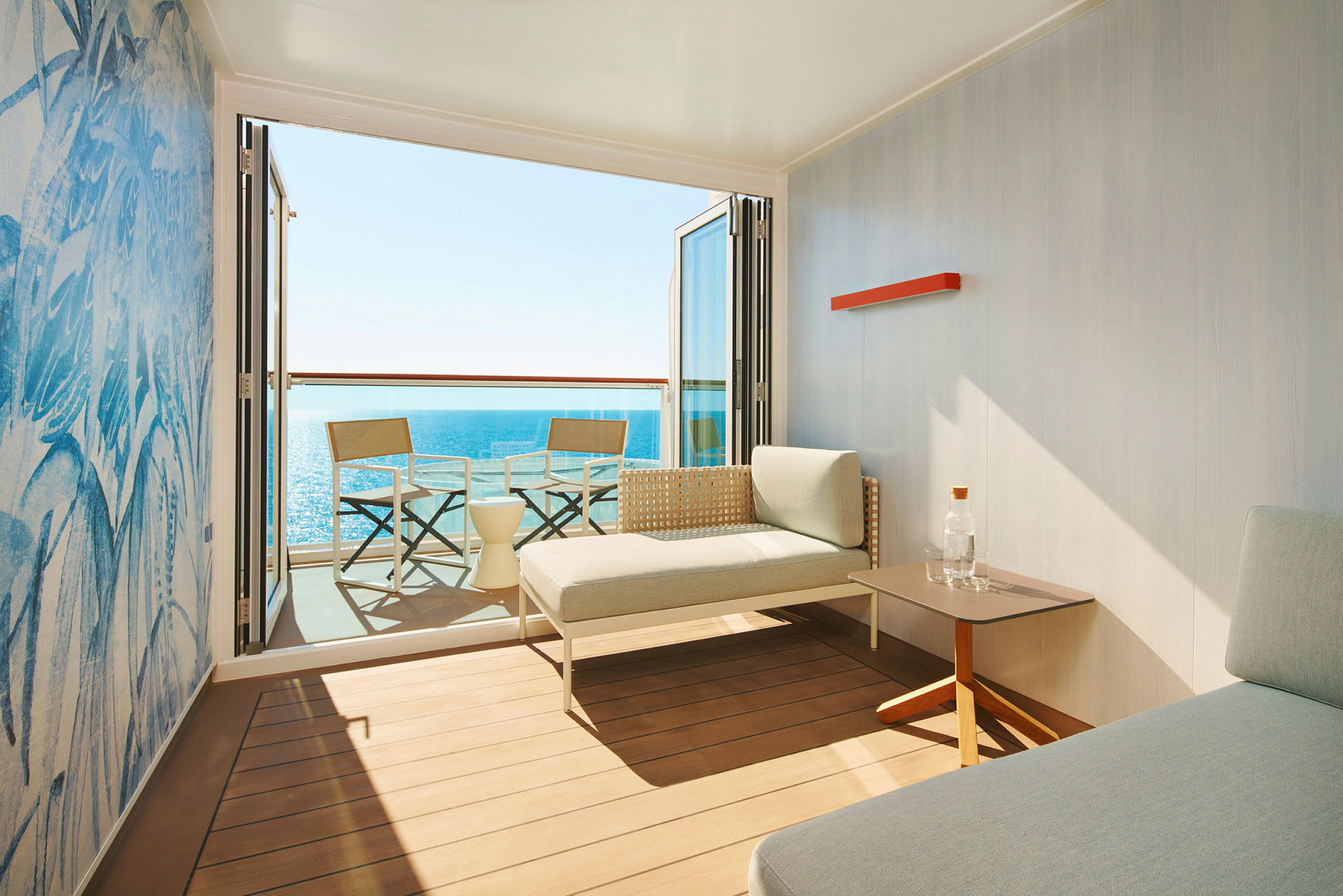 Et moderne hotelværelse med en terrasse, to stole og et bord samt udsigt over havet. (AI-genereret tekst)