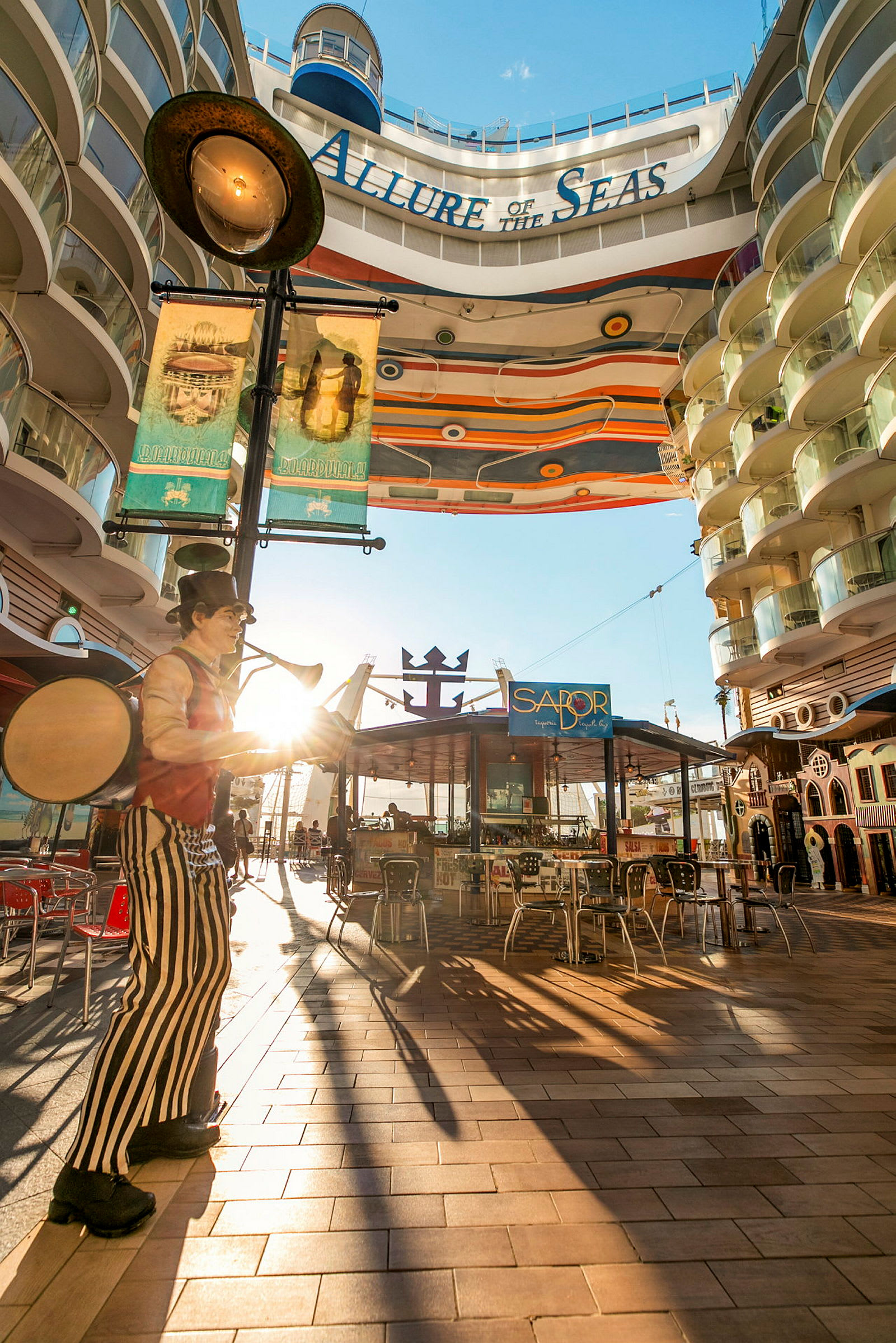 Billede af et solrigt område ombord på krydstogtskibet Allure of the Seas, med en dekorativ gang og restauranter. (AI-genereret tekst)