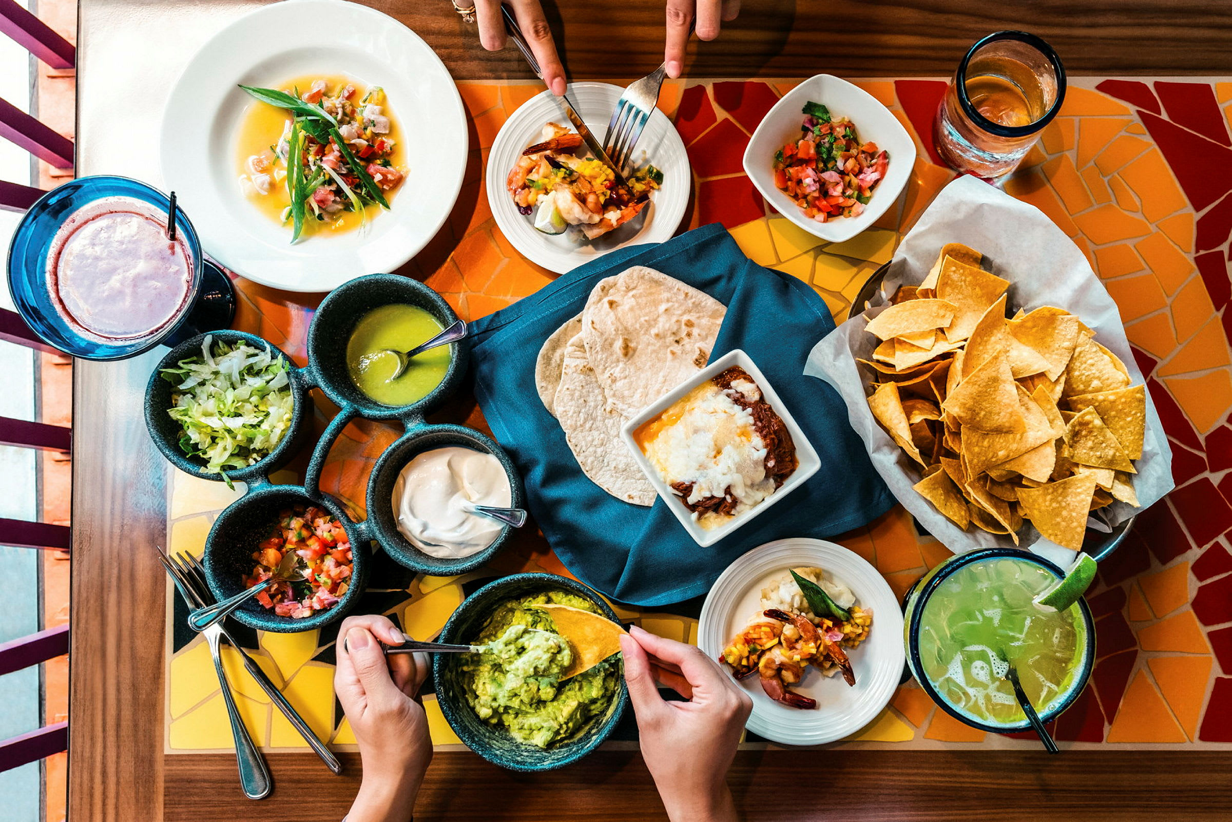 Et bord dækket med mexicansk mad, herunder tacos, guacamole, chips og salsaer. (AI-genereret tekst)