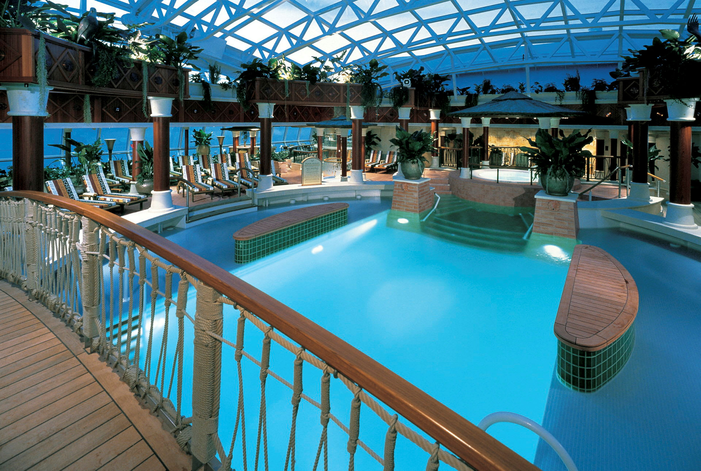 Indendørs swimmingpool med bro og liggestole. (AI-genereret tekst)
