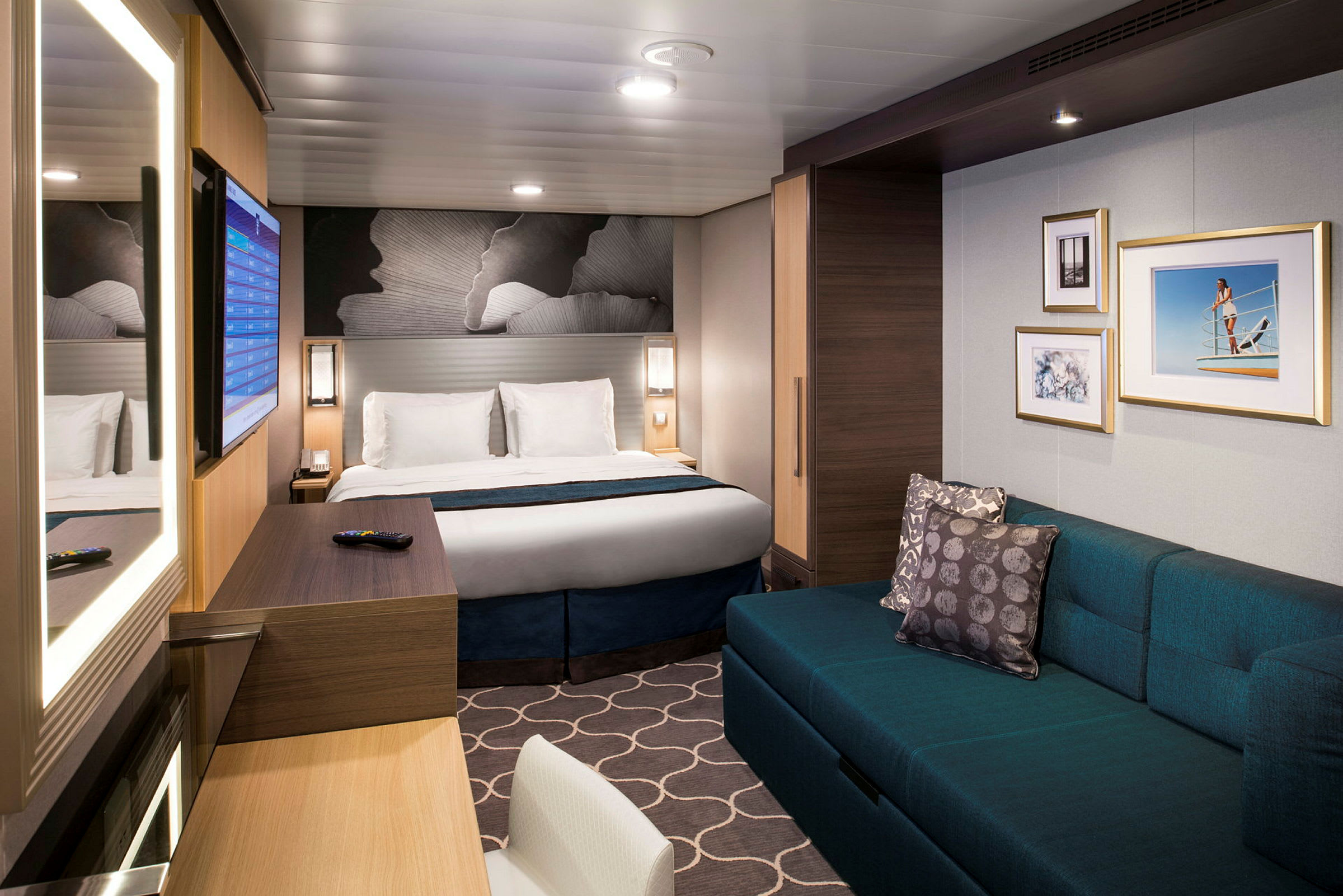 Et moderne hotelværelse med en dobbeltseng, en sofa, vægdekorationer og et skrivebord med spejl. (AI-genereret tekst)