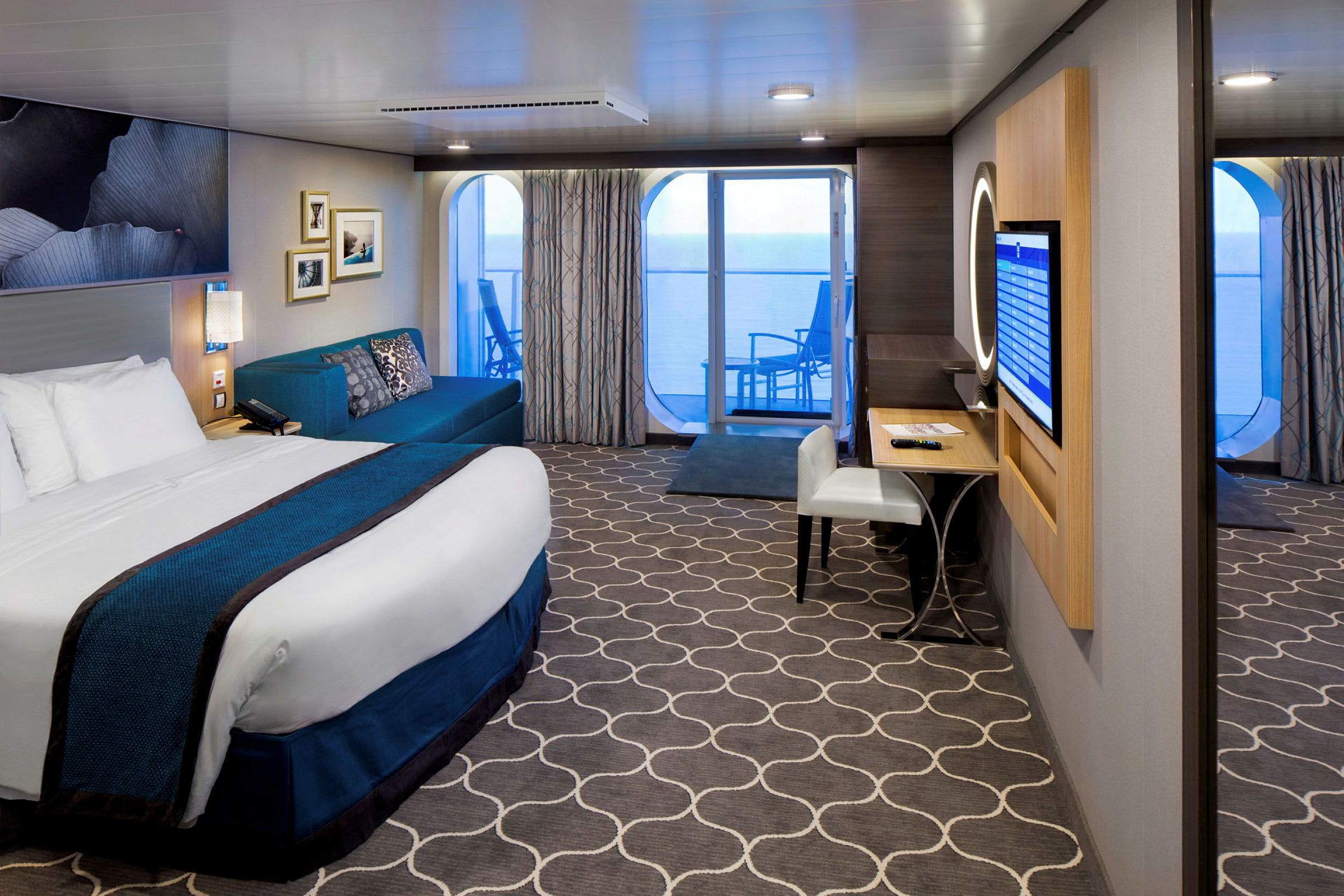 Et hotelværelse med seng, sofa, skrivebord og altan med udsigt over havet. (AI-genereret tekst)