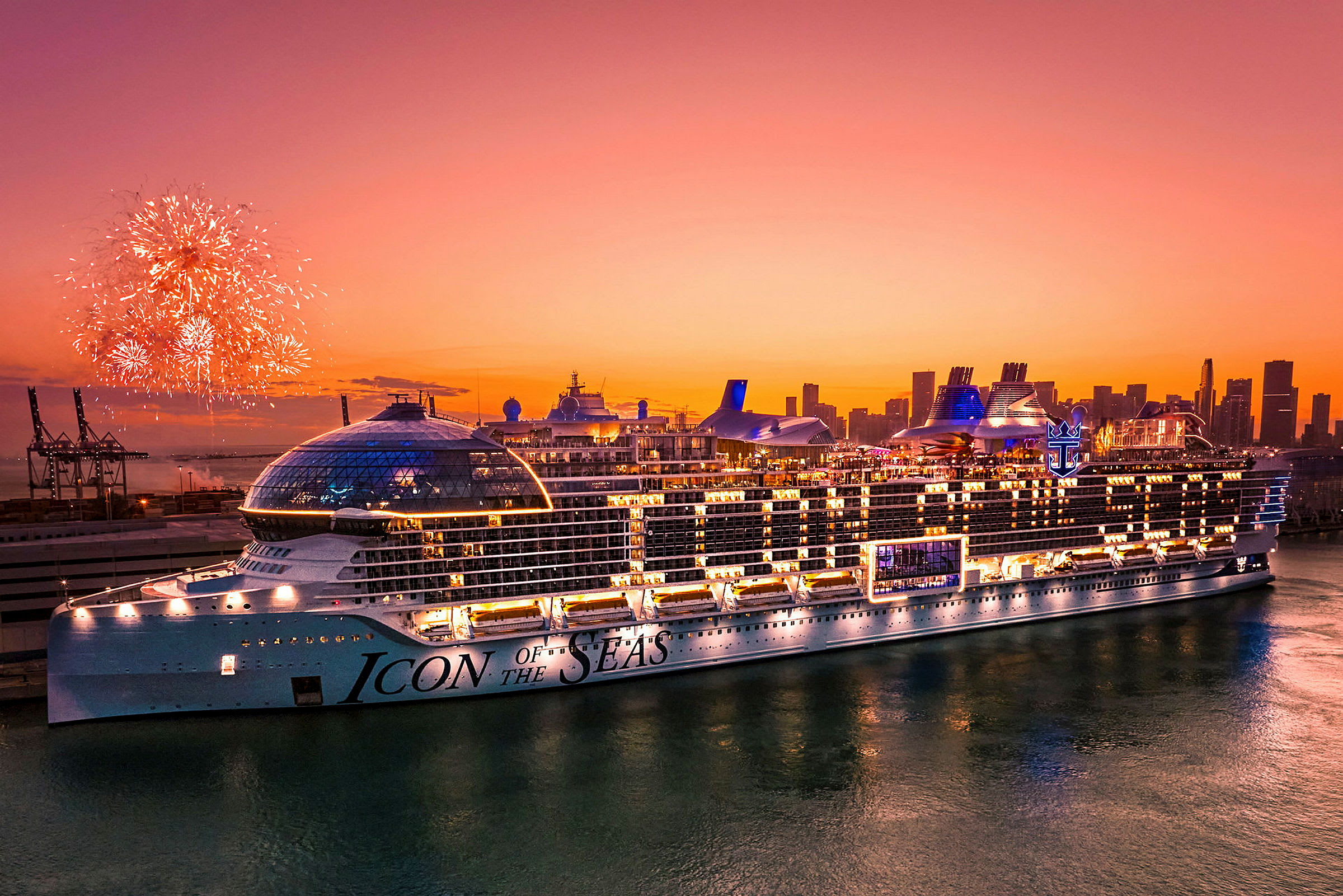 Et stort krydstogtskib med navnet 'Icon of the Seas' synligt mod en solnedgang, mens fyrværkeri oplyser nattehimlen. (AI-genereret tekst)