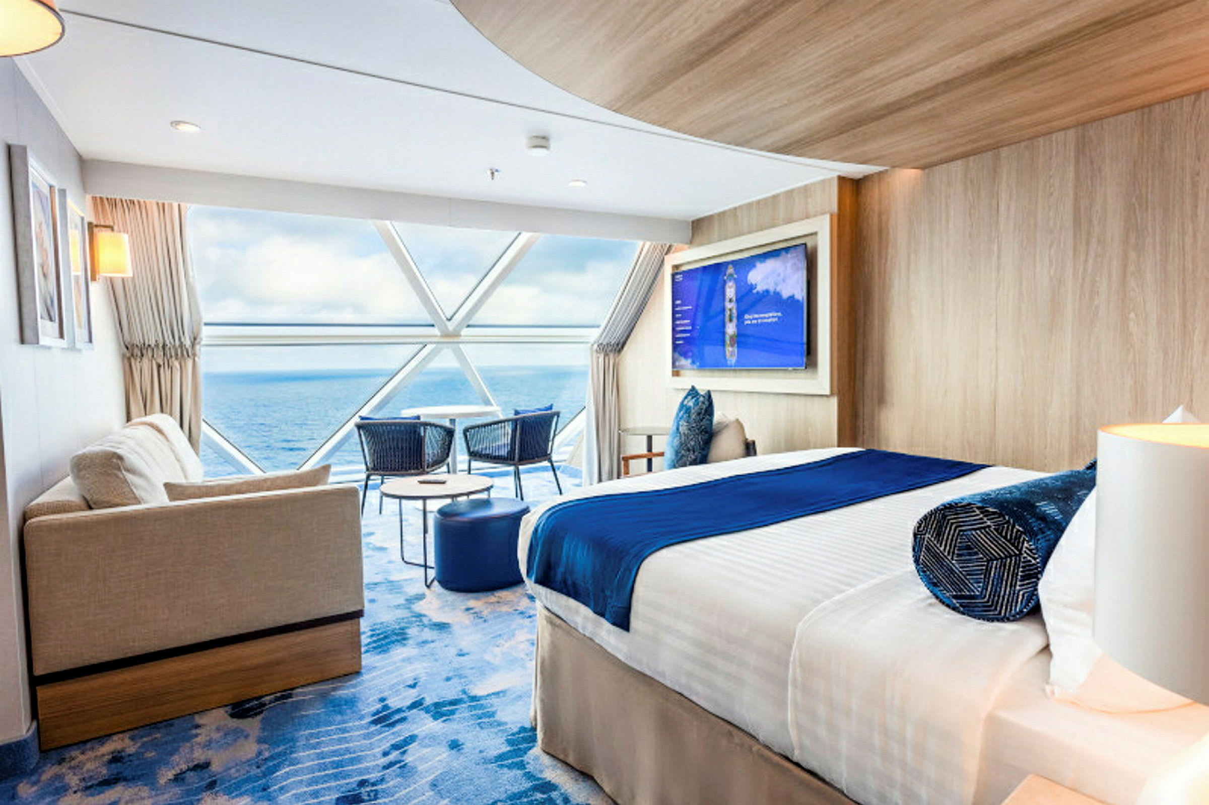 Moderne hotelværelse med seng, sofa og udsigt over havet gennem store vinduer. (AI-genereret tekst)