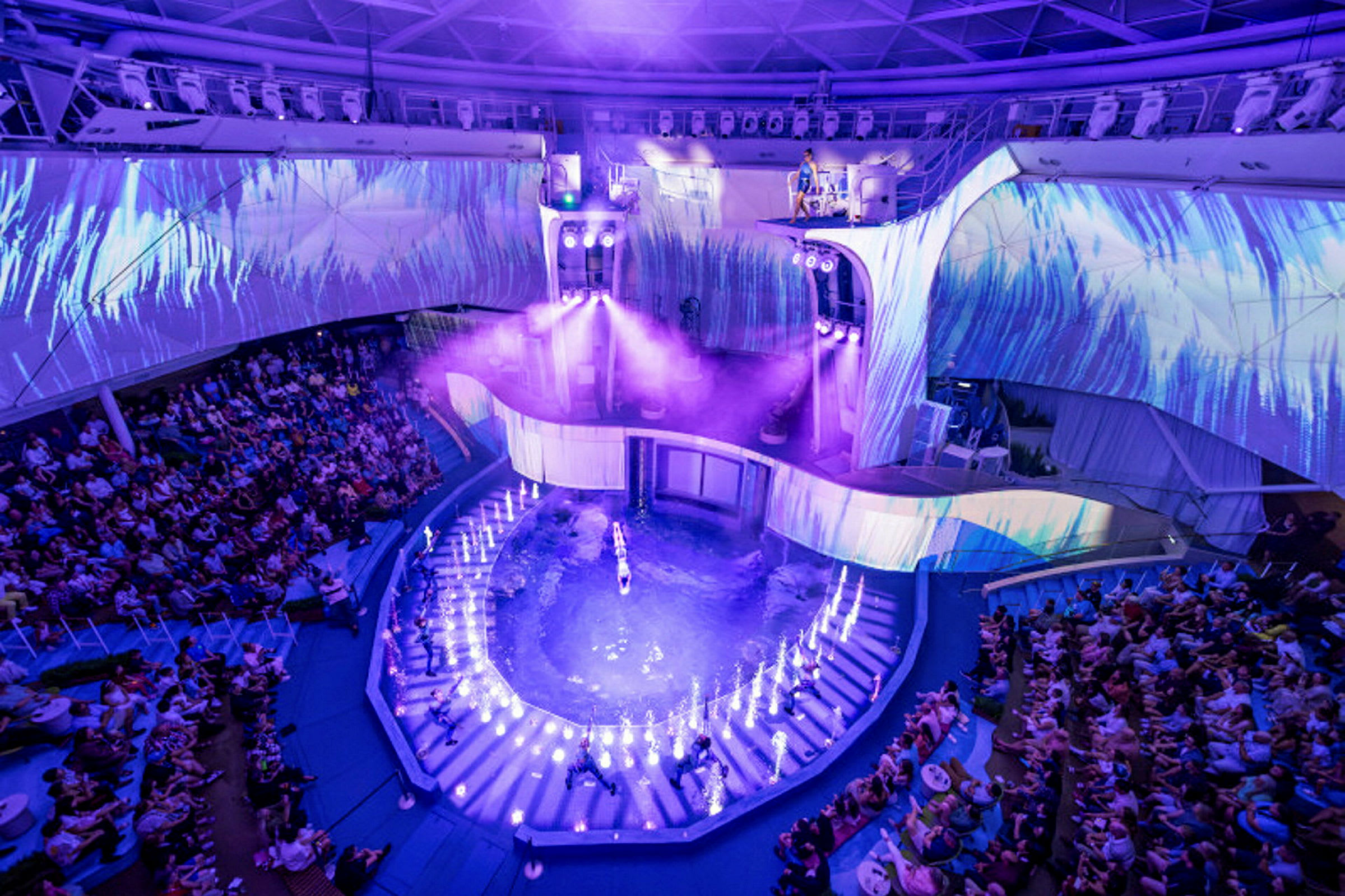 En arena med et vandshow. Publikum sidder omkring det oplyste område. (AI-genereret tekst)