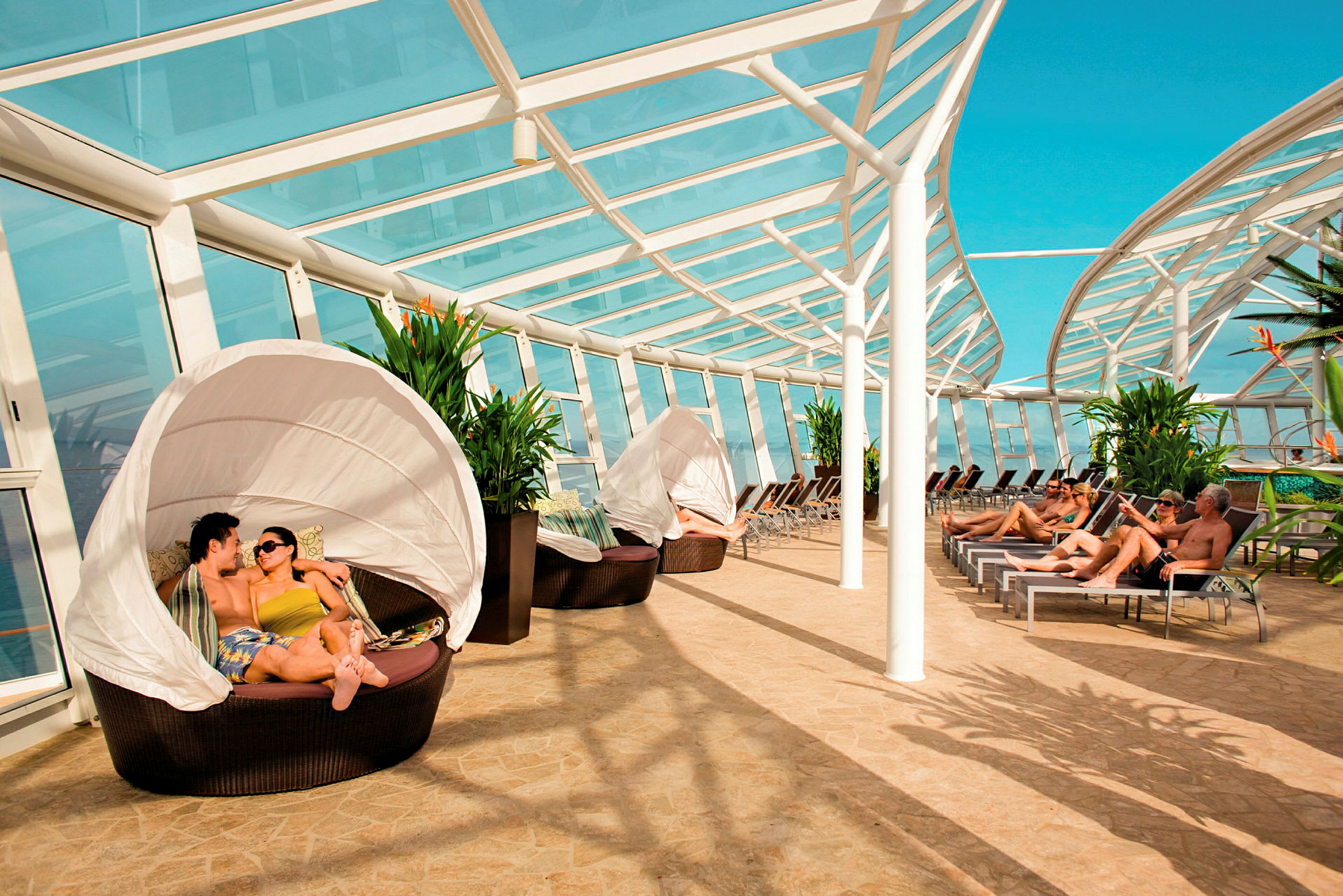 Solarium med glastag, liggestole og siddegrupper ved siden af grønne planter. (AI-genereret tekst)