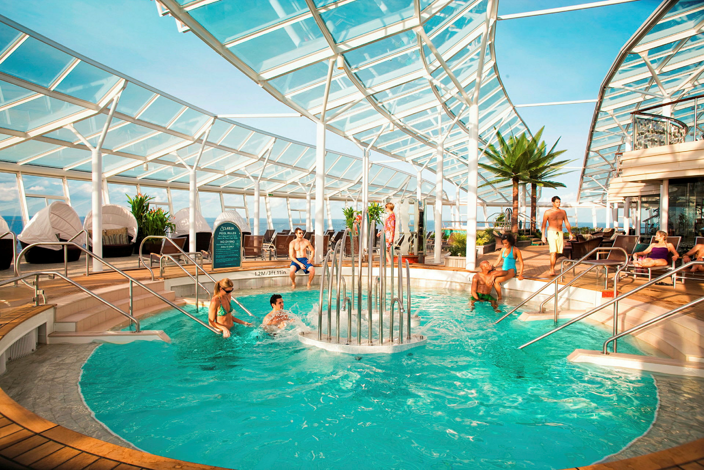 En indendørs pool med en springvand omgivet af liggestole og planter. (AI-genereret tekst)