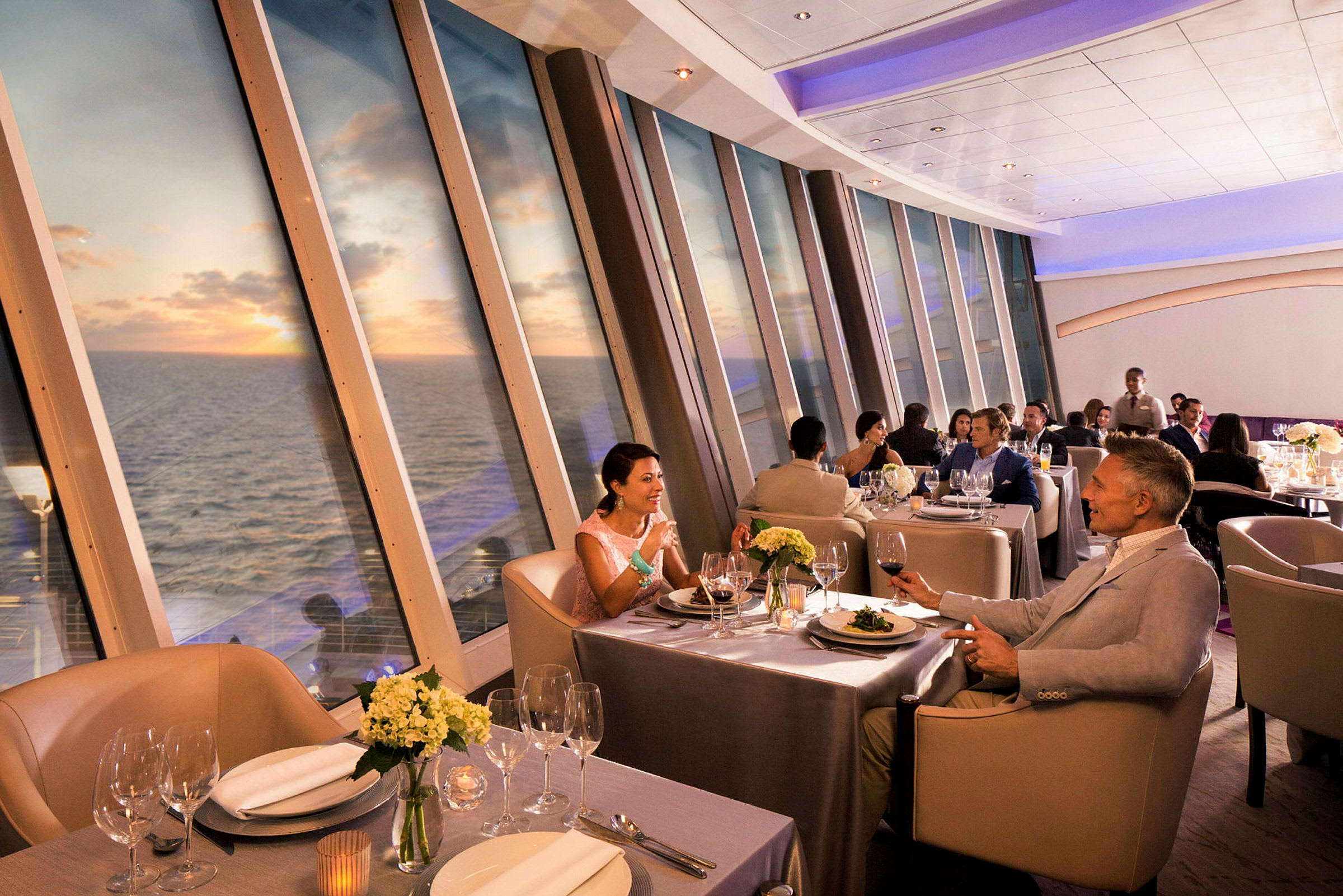 Elegant restaurant med panoramisk udsigt over havet og solnedgang. (AI-genereret tekst)