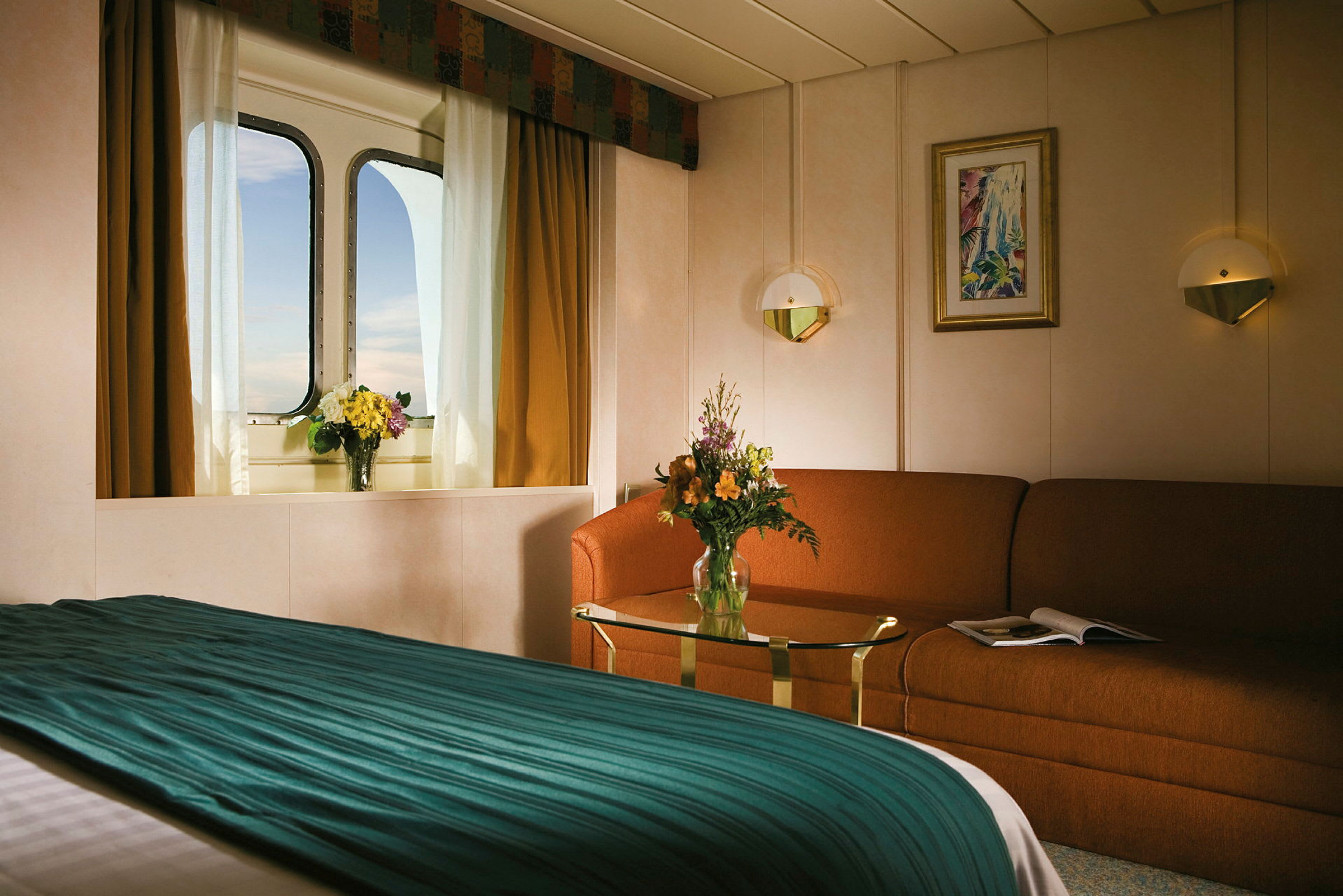 Billede af et hyggeligt hotelværelse med sofabord og seng, samt et vindue med udsigt og blomster. (AI-genereret tekst)