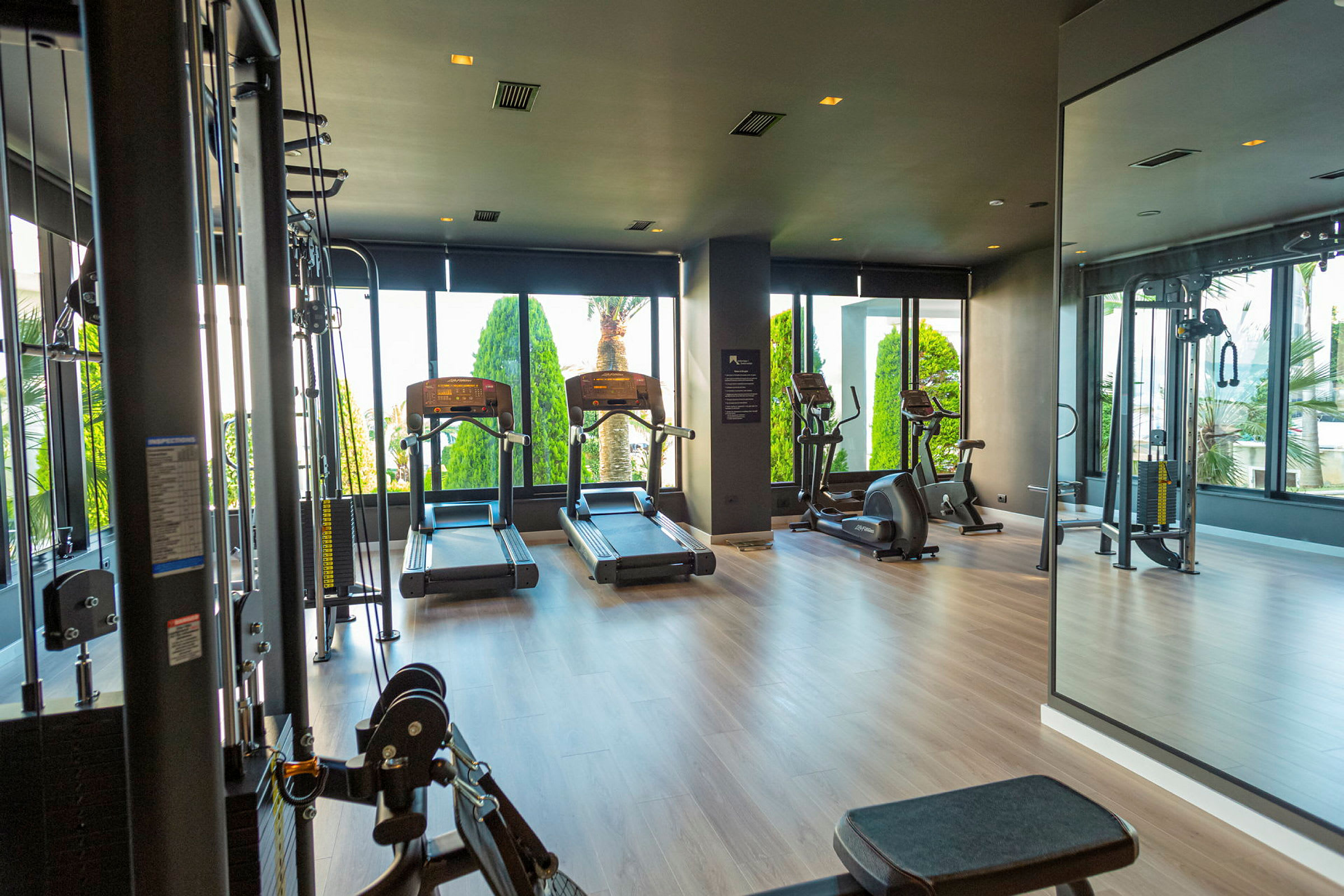 Et moderne fitnesscenter med træningsmaskiner og store vinduer. (AI-genereret tekst)