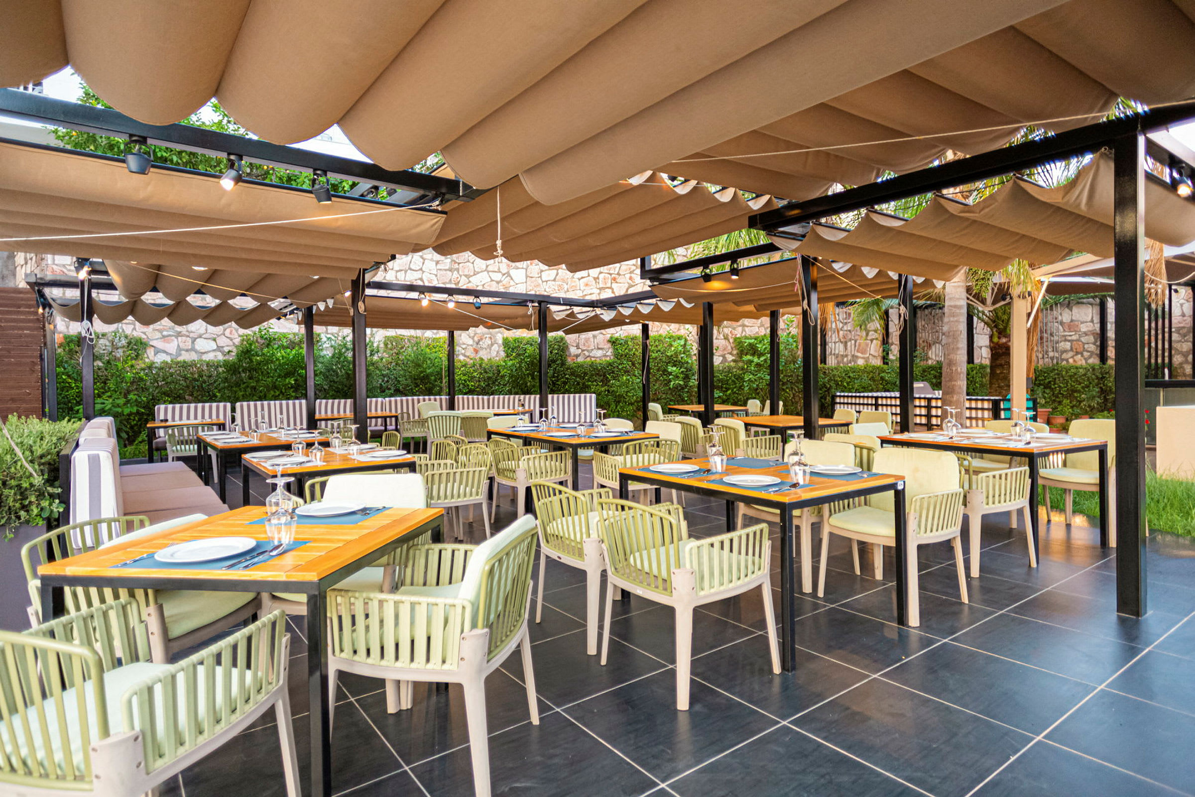 Udendørs restaurant med borde, stole og solbeskyttelsestag. (AI-genereret tekst)