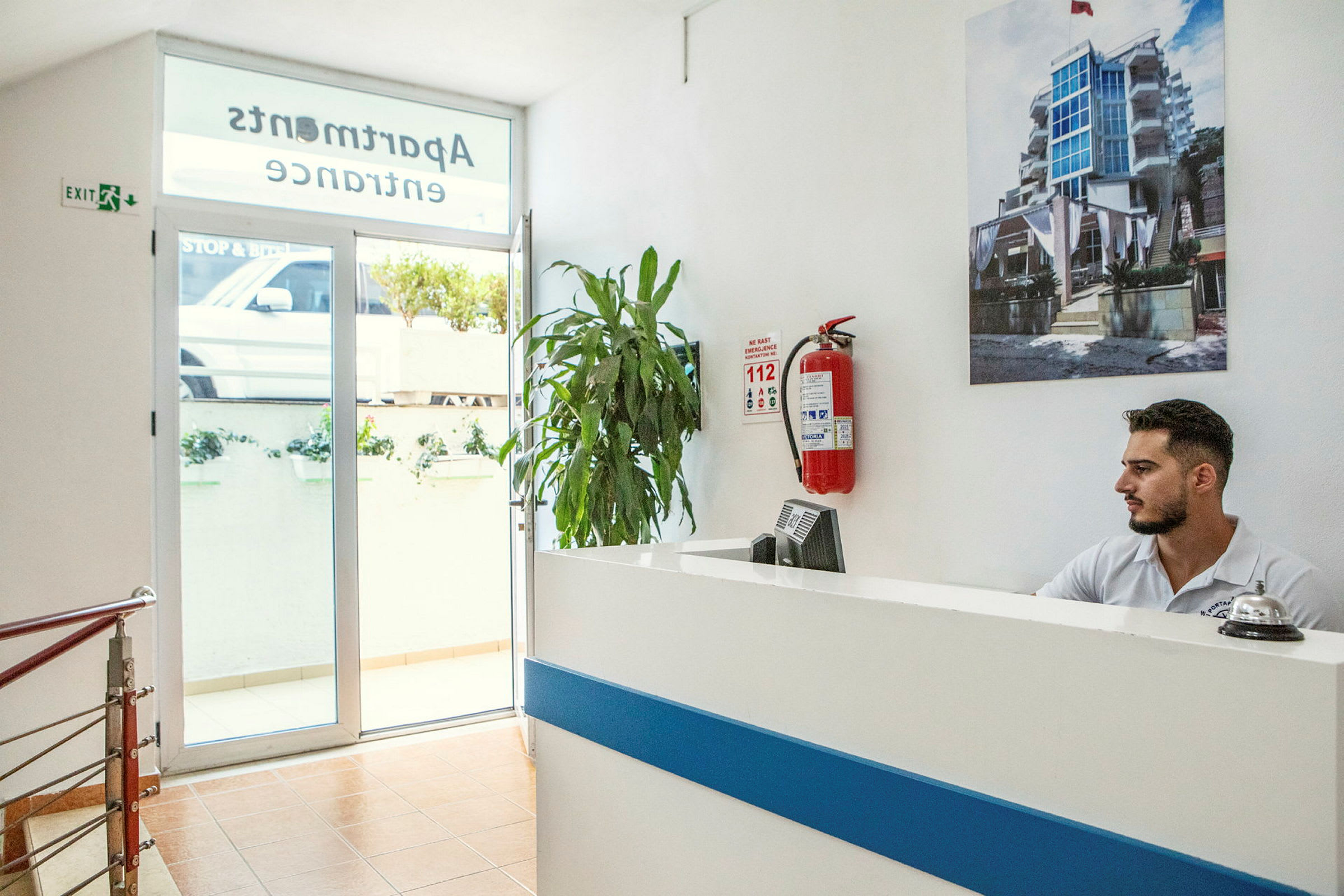 Reception i en lejlighedsbygning med en plante og en brandslukker på væggen. (AI-genereret tekst)