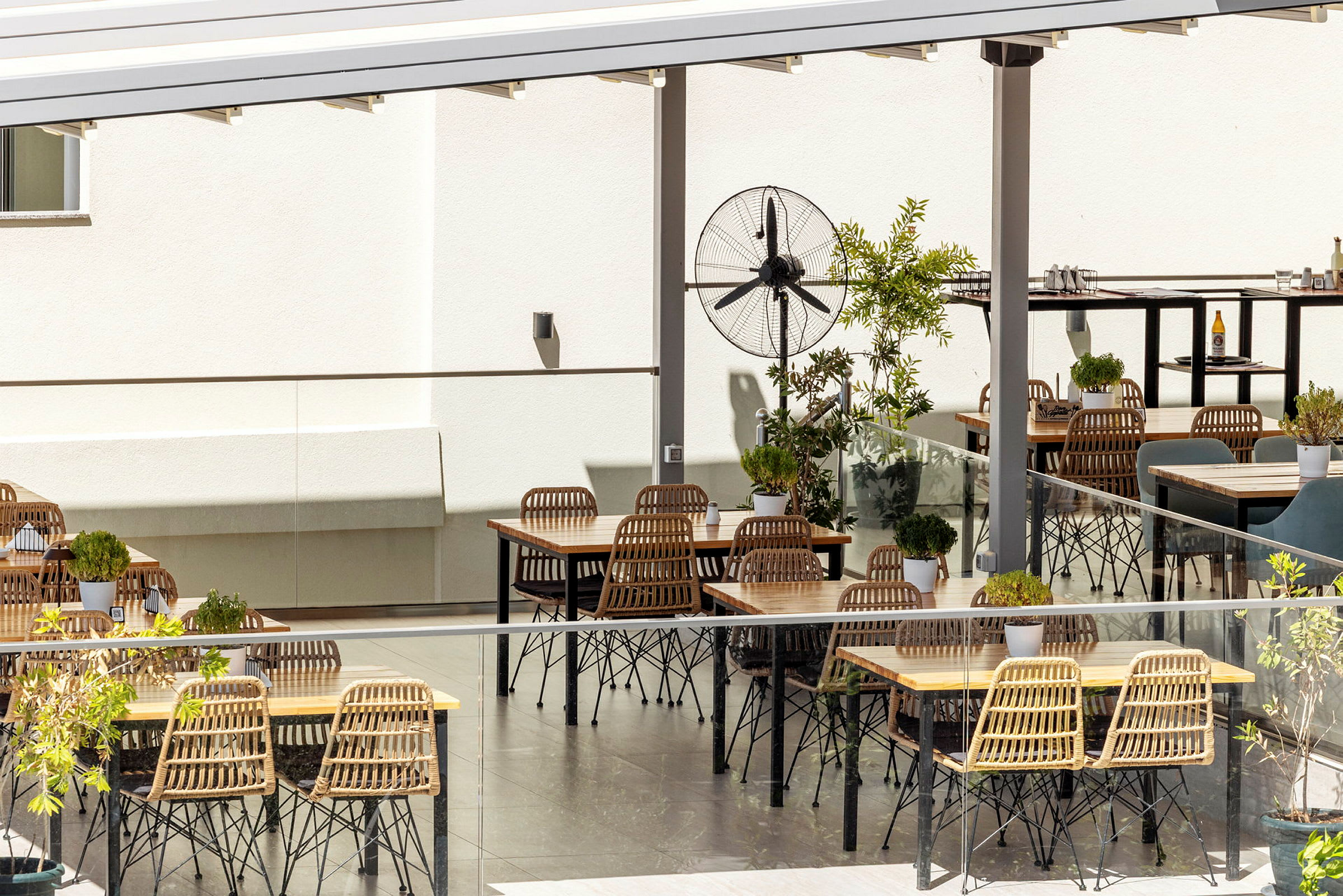 Udendørs serveringsområde med borde, stole og planter. (AI-genereret tekst)