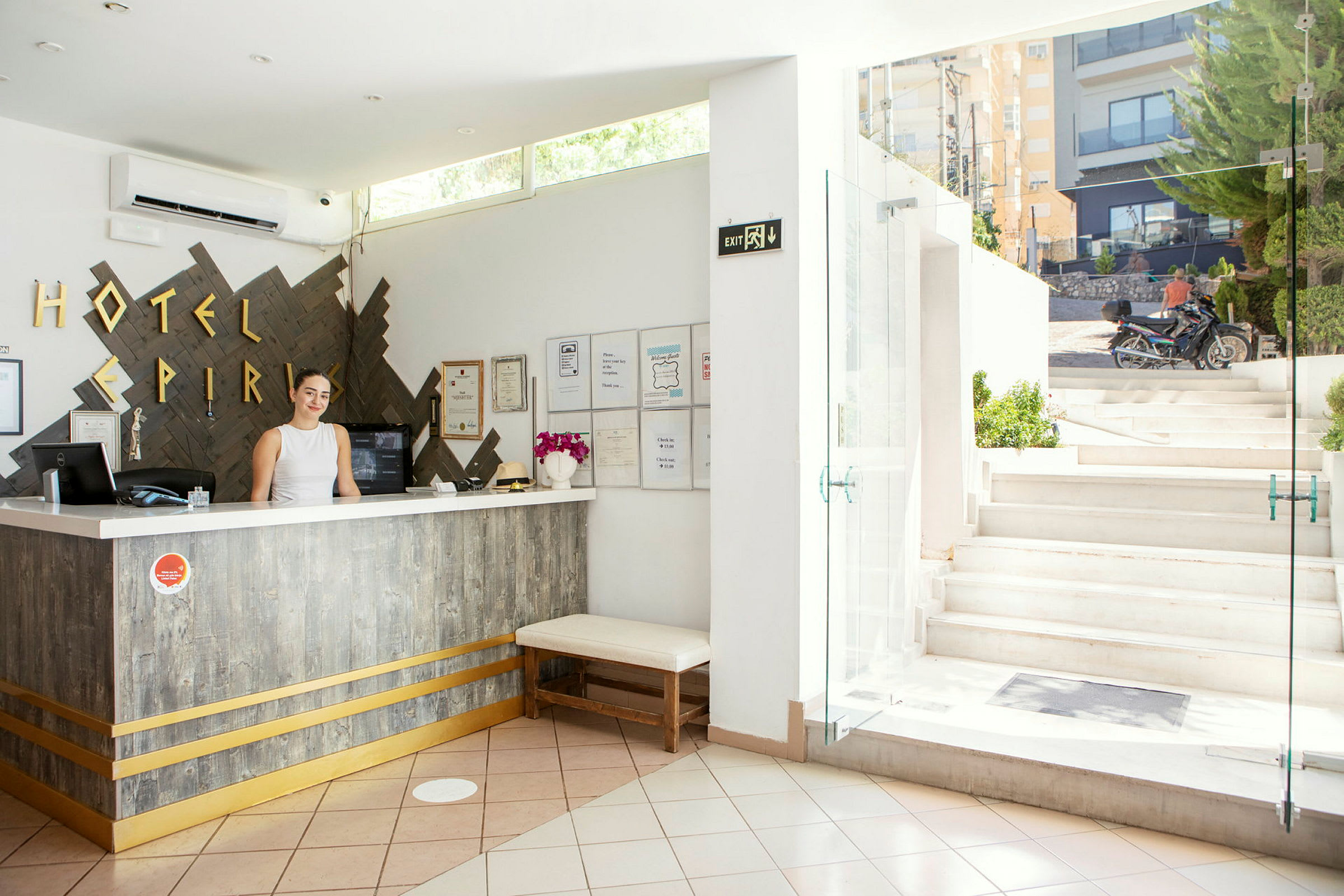 Hotellets lobby med reception og åbning mod en udendørs trappe. (AI-genereret tekst)