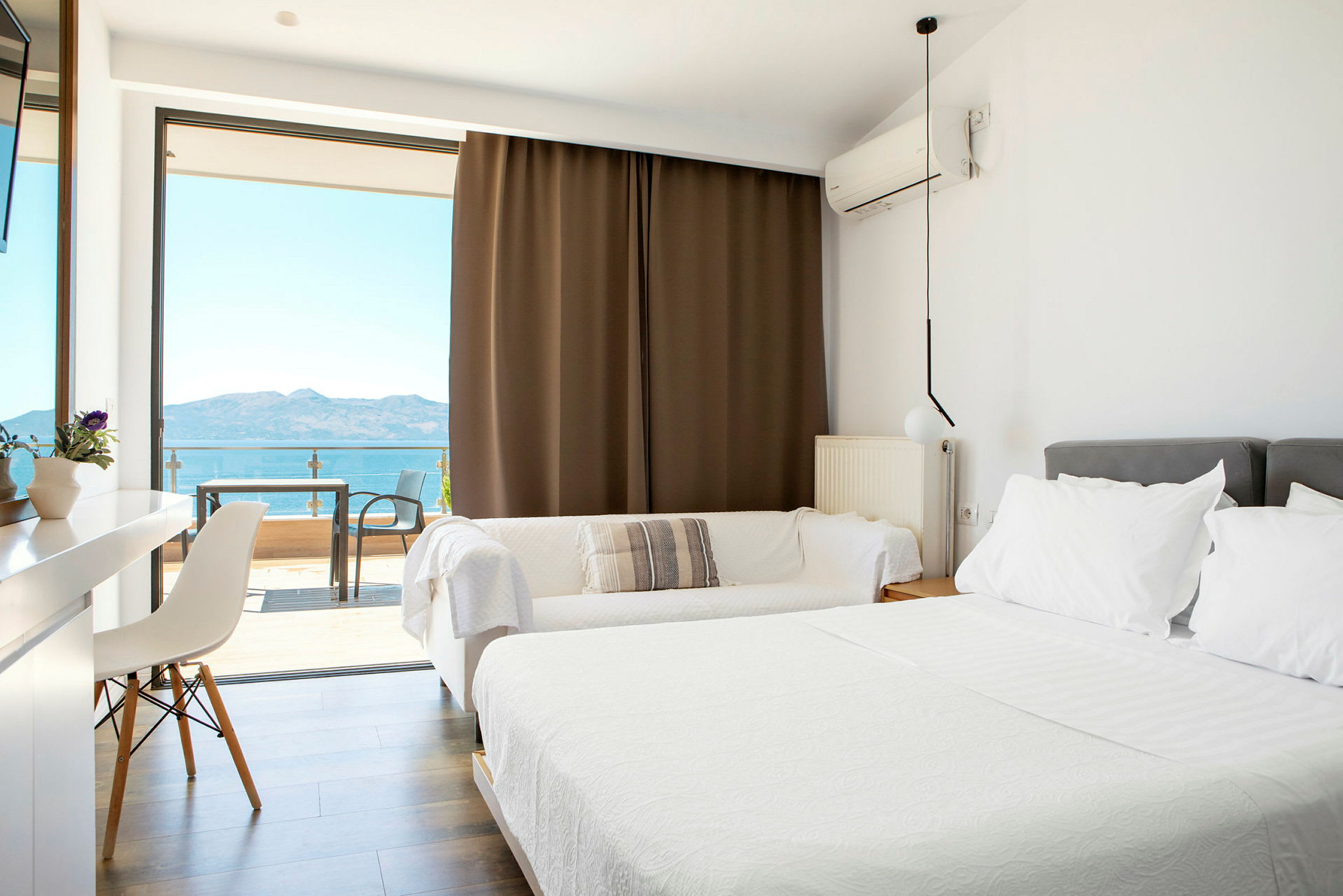 Lyst hotelværelse med dobbeltseng og balkon med havudsigt. (AI-genereret tekst)