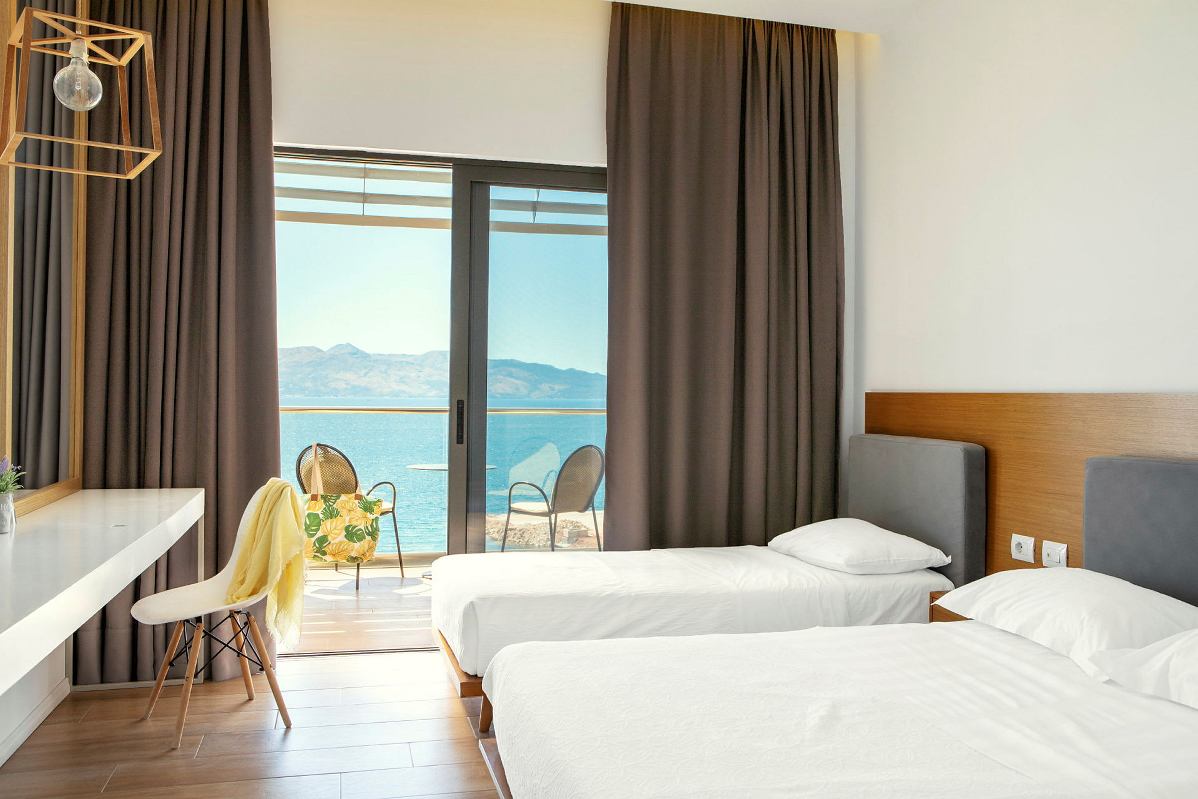Hotelværelse med to enkeltsenge og adgang til en balkon med udsigt over havet. (AI-genereret tekst)