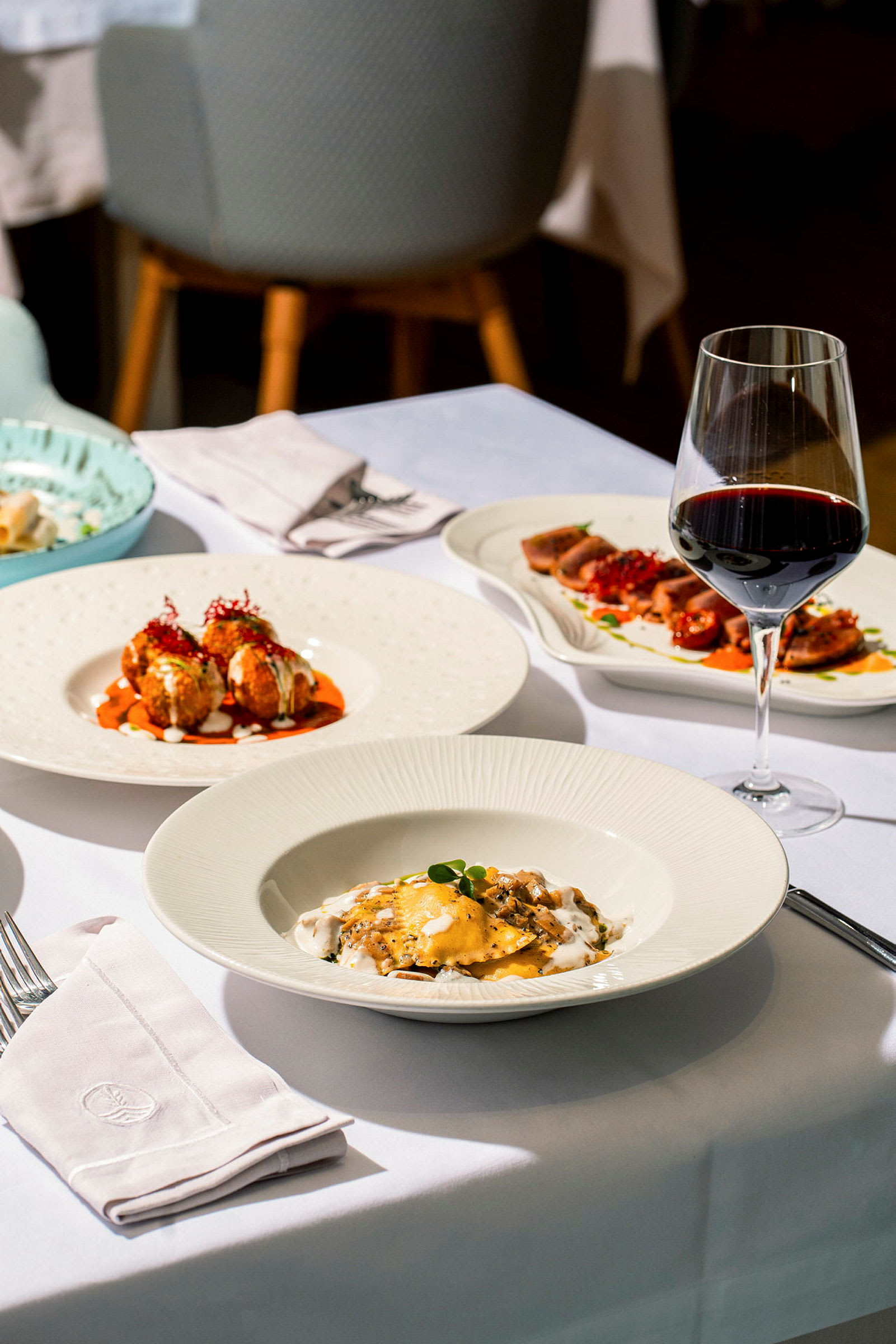Et dækket restaurantbord med forskellige retter og et glas rødvin. (AI-genereret tekst)