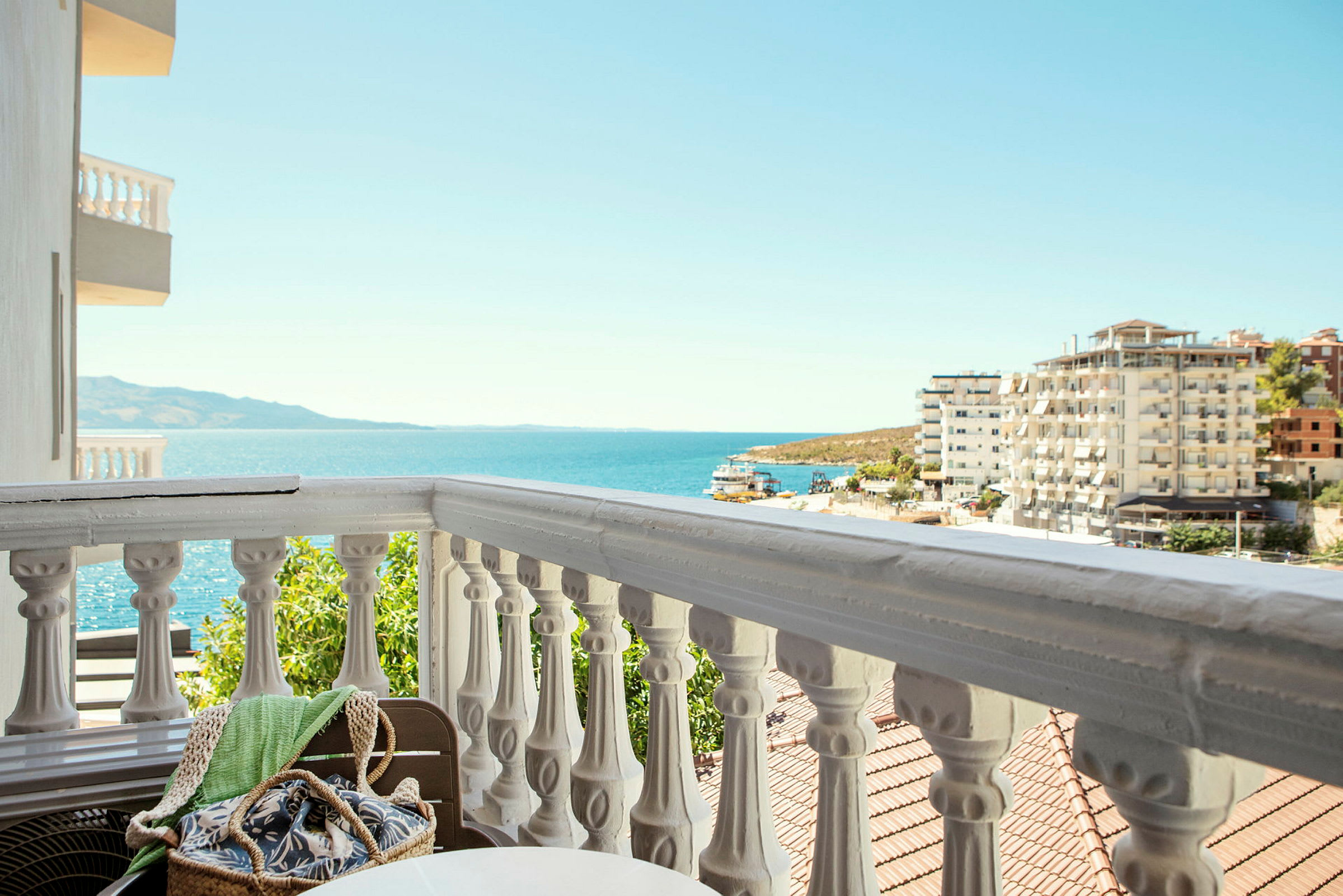 Udsigt fra en balkon med hvid balustrade og havet i baggrunden. (AI-genereret tekst)