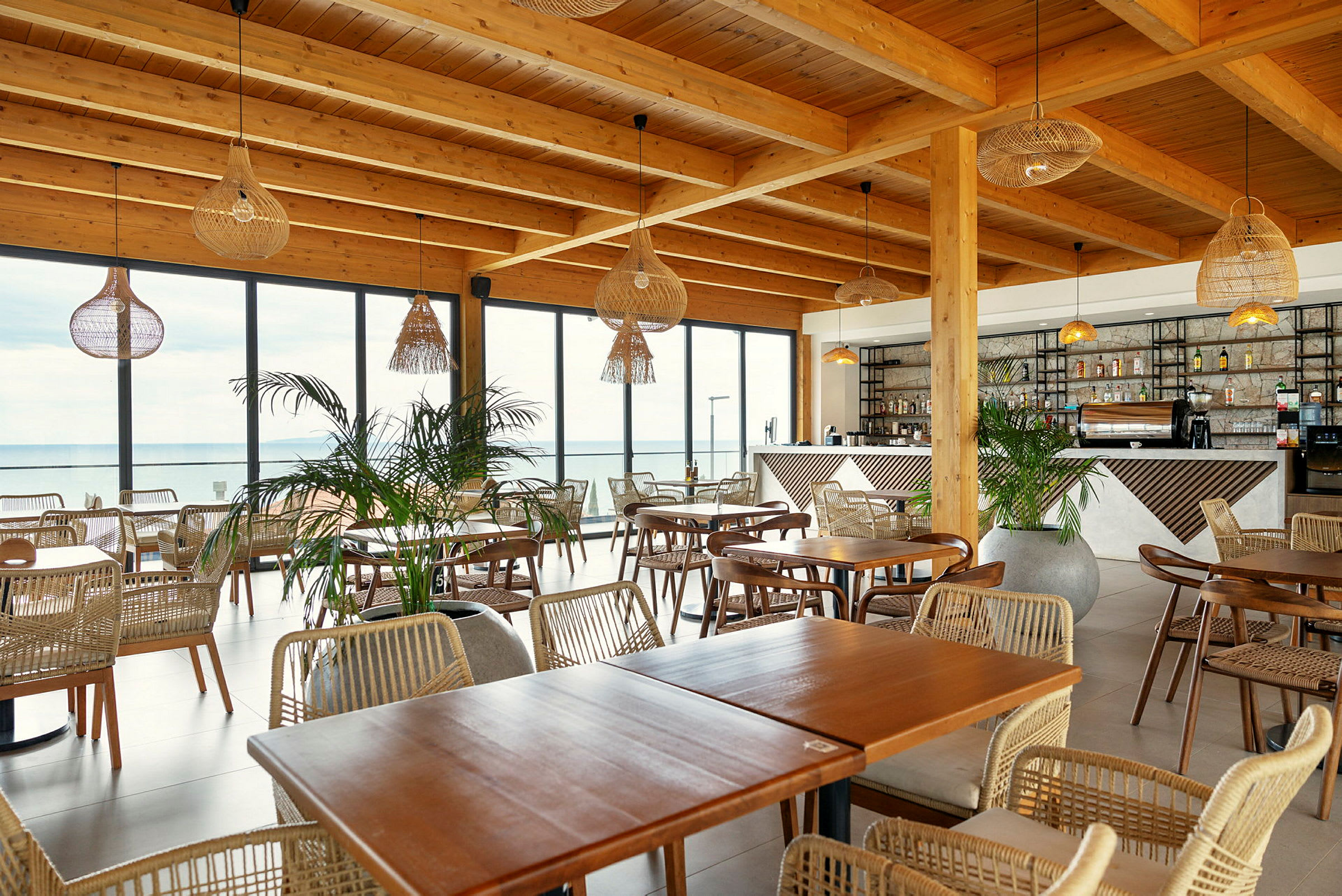 Restaurant med træmøbler, store glasvinduer og hængende lamper. (AI-genereret tekst)