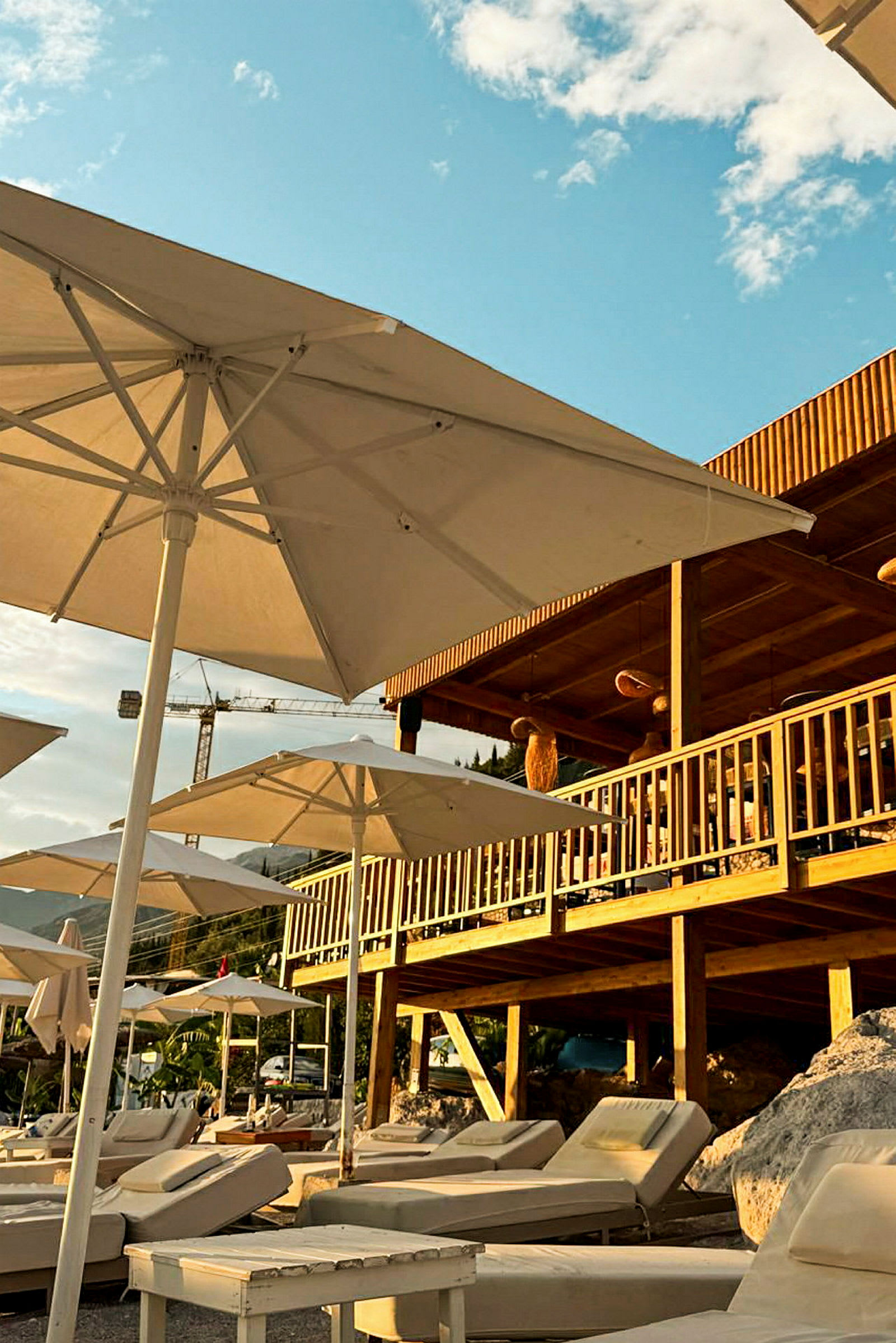 Liggestole og parasoller på en terrasse ved en strand. (AI-genereret tekst)