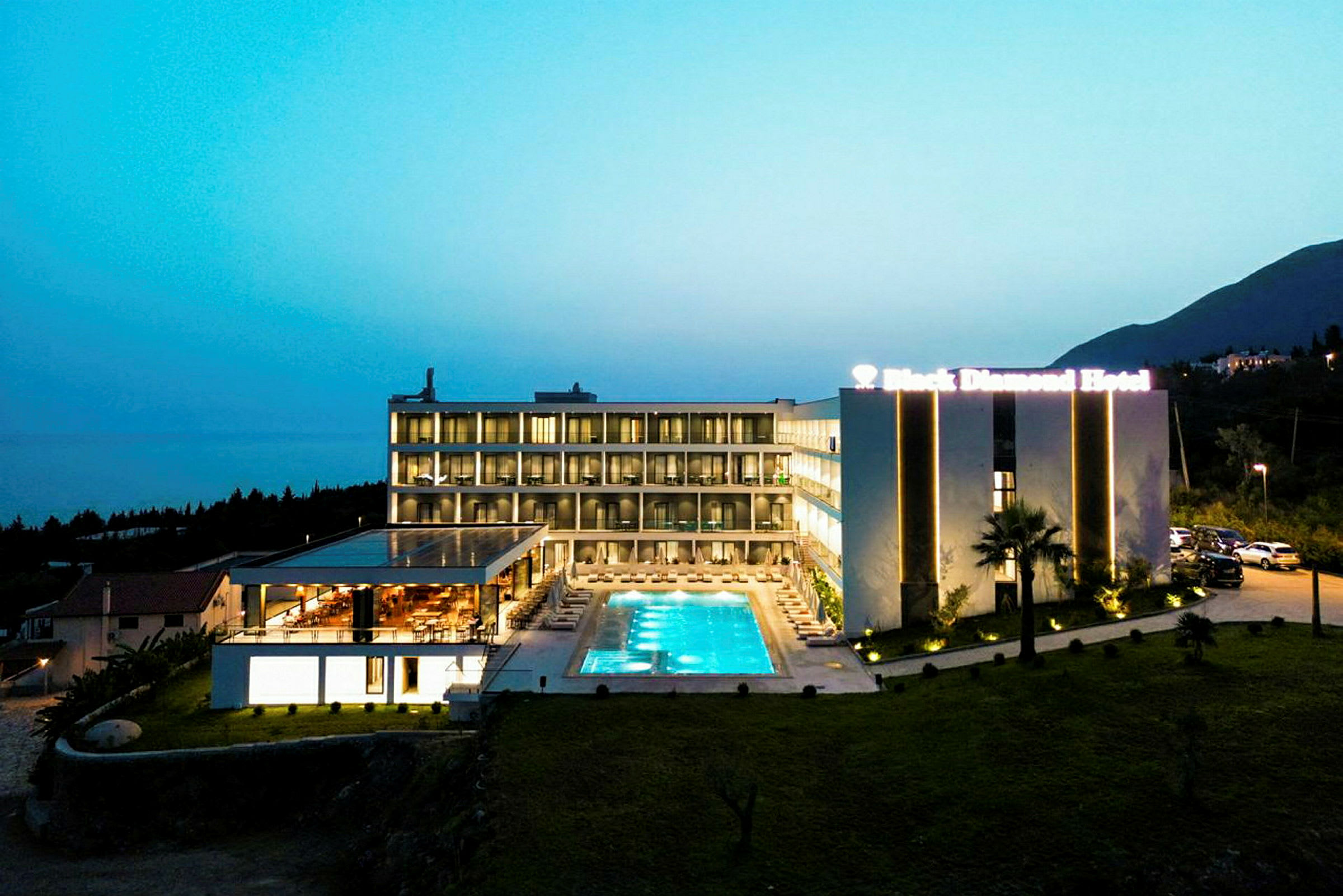 Moderne hotel med udendørs pool oplyst om aftenen. (AI-genereret tekst)