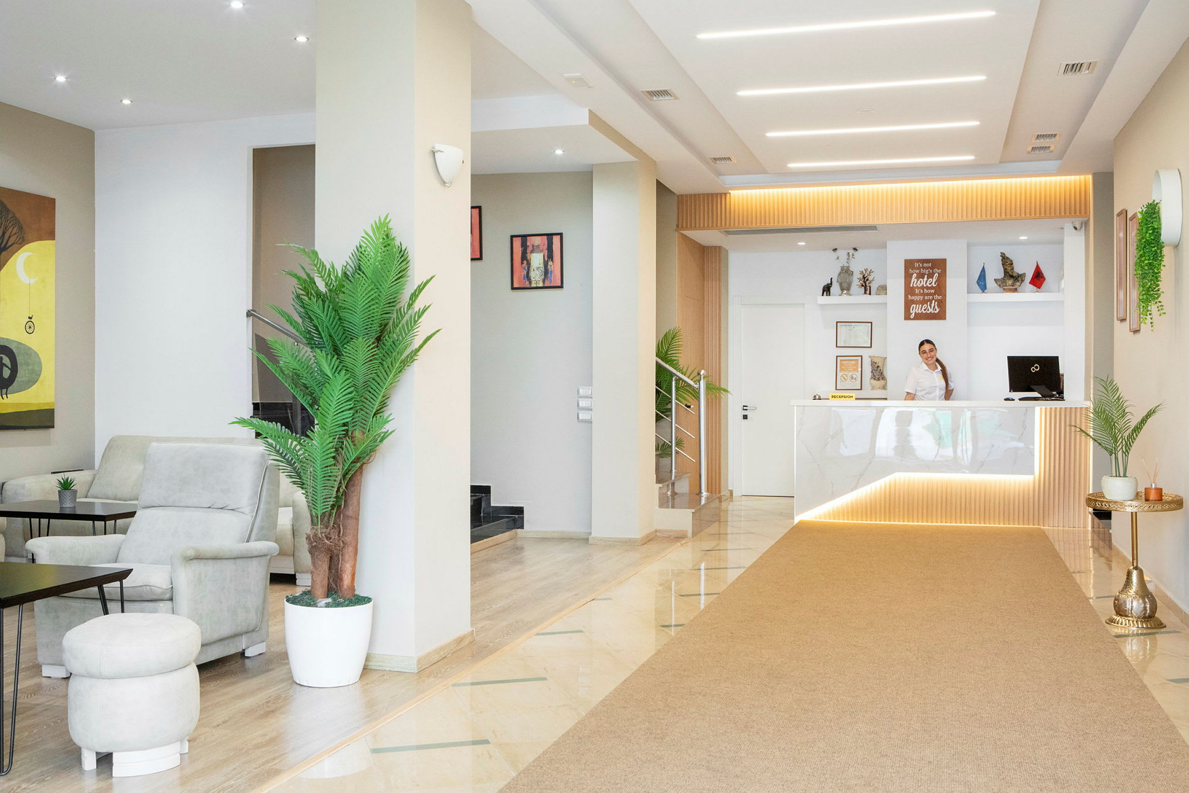 Dette er en hotellfoyer med en receptionsdisk, siddepladser og grønne dekorative planter. (AI-genereret tekst)