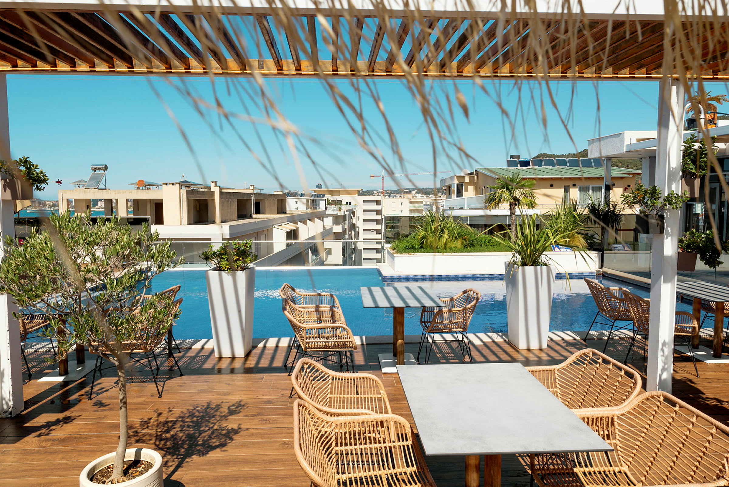 En tagterrasse med pool, liggestole og borde samt udsigt over de omkringliggende bygninger. (AI-genereret tekst)