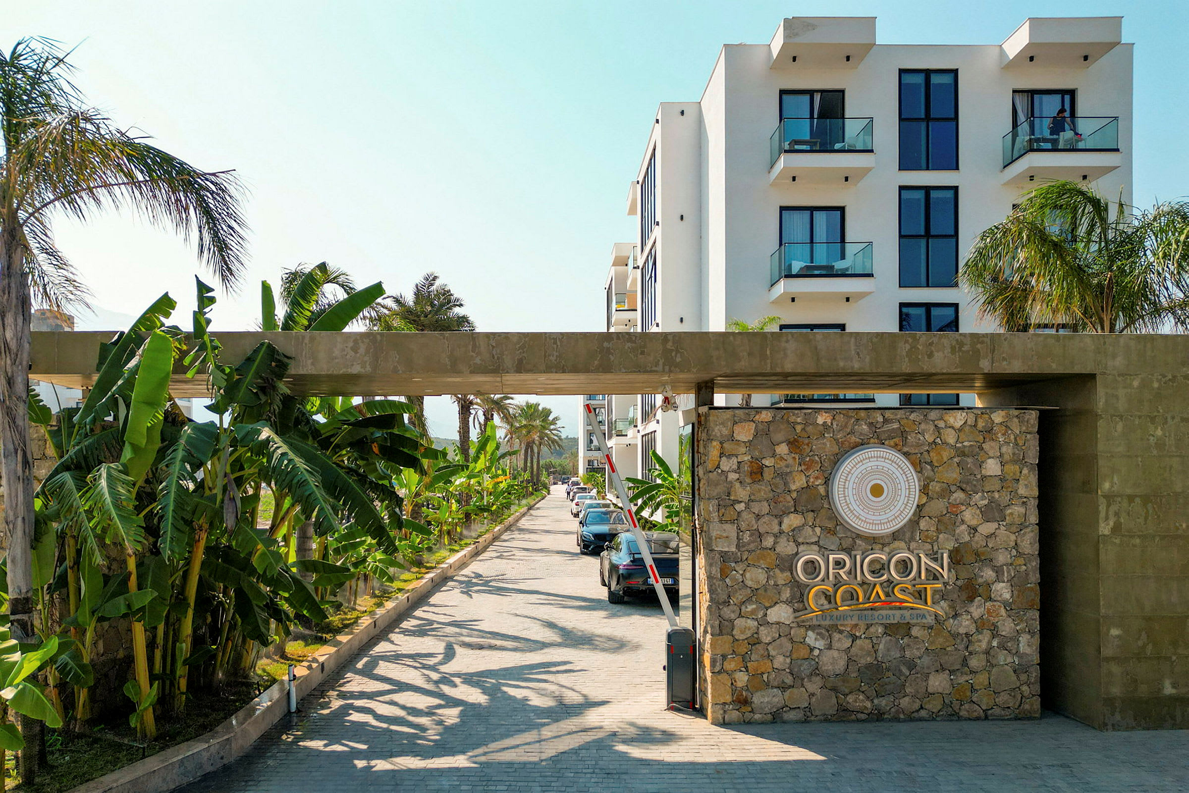 Indgangen til Oricon Coast Luxury Resort & Spa med stenmur og logo. (AI-genereret tekst)