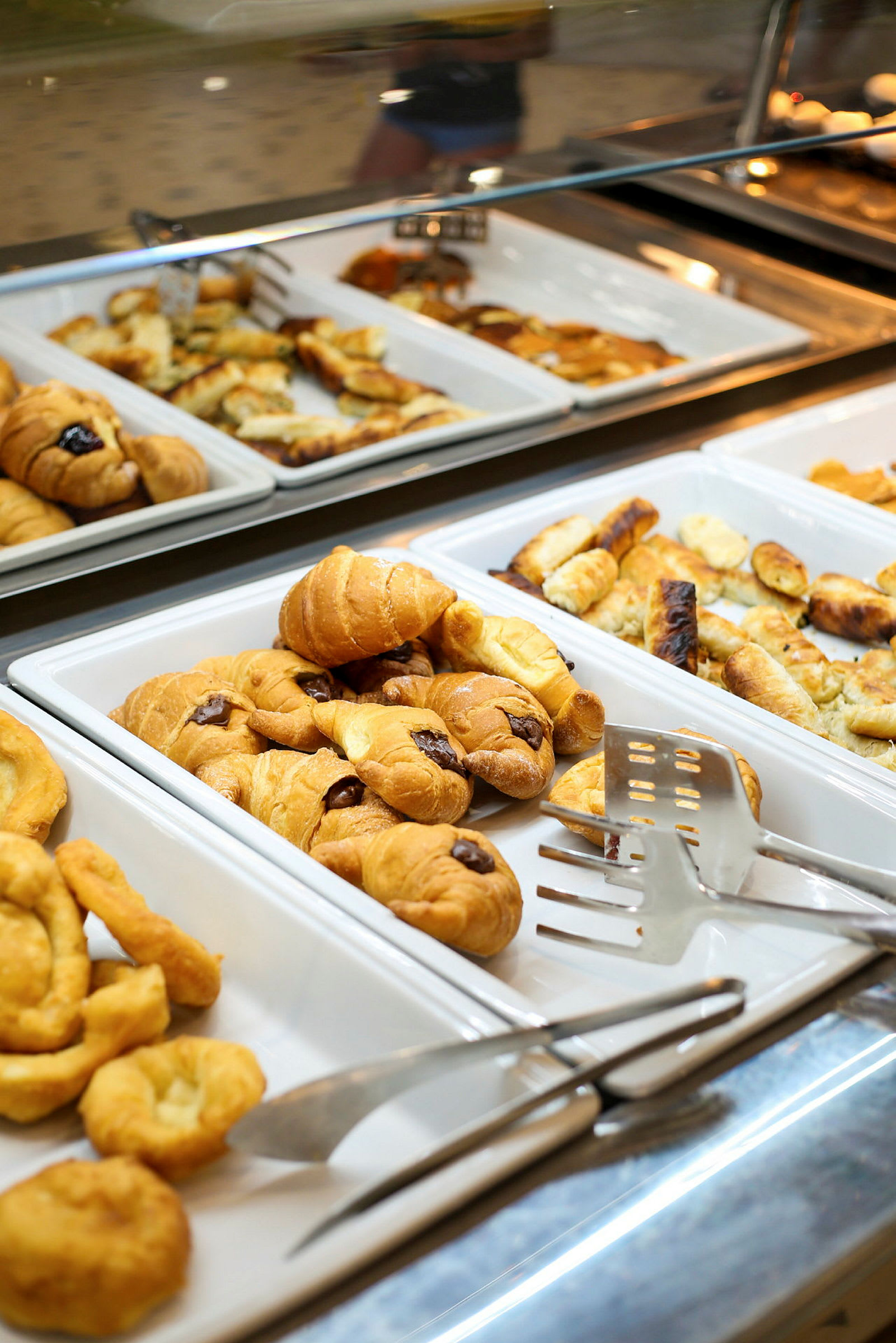 Udstilling med bagværk på forskellige serveringsfade, inklusive croissanter. (AI-genereret tekst)