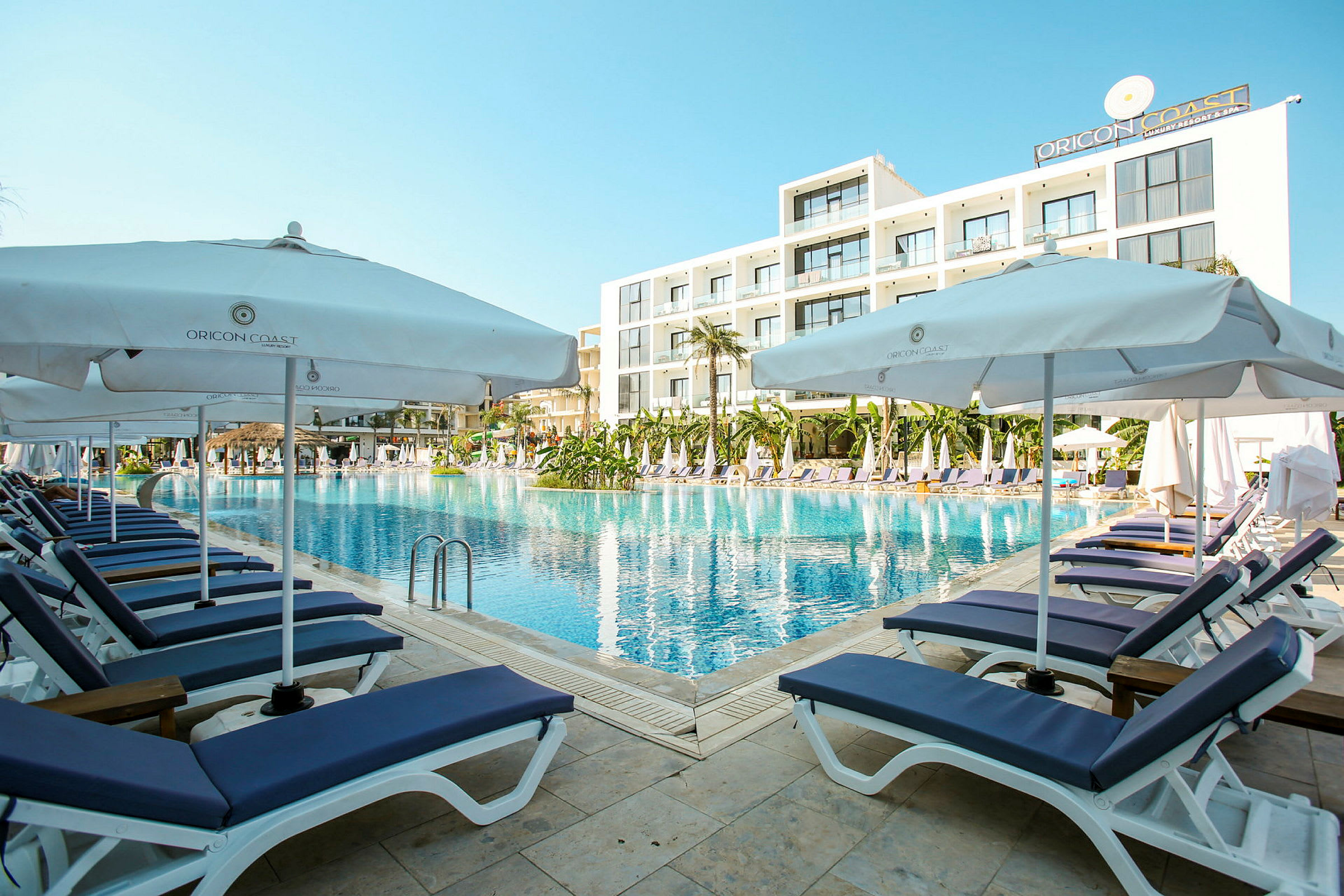 En poolkant med liggestole og parasoller ved et moderne hotel. (AI-genereret tekst)