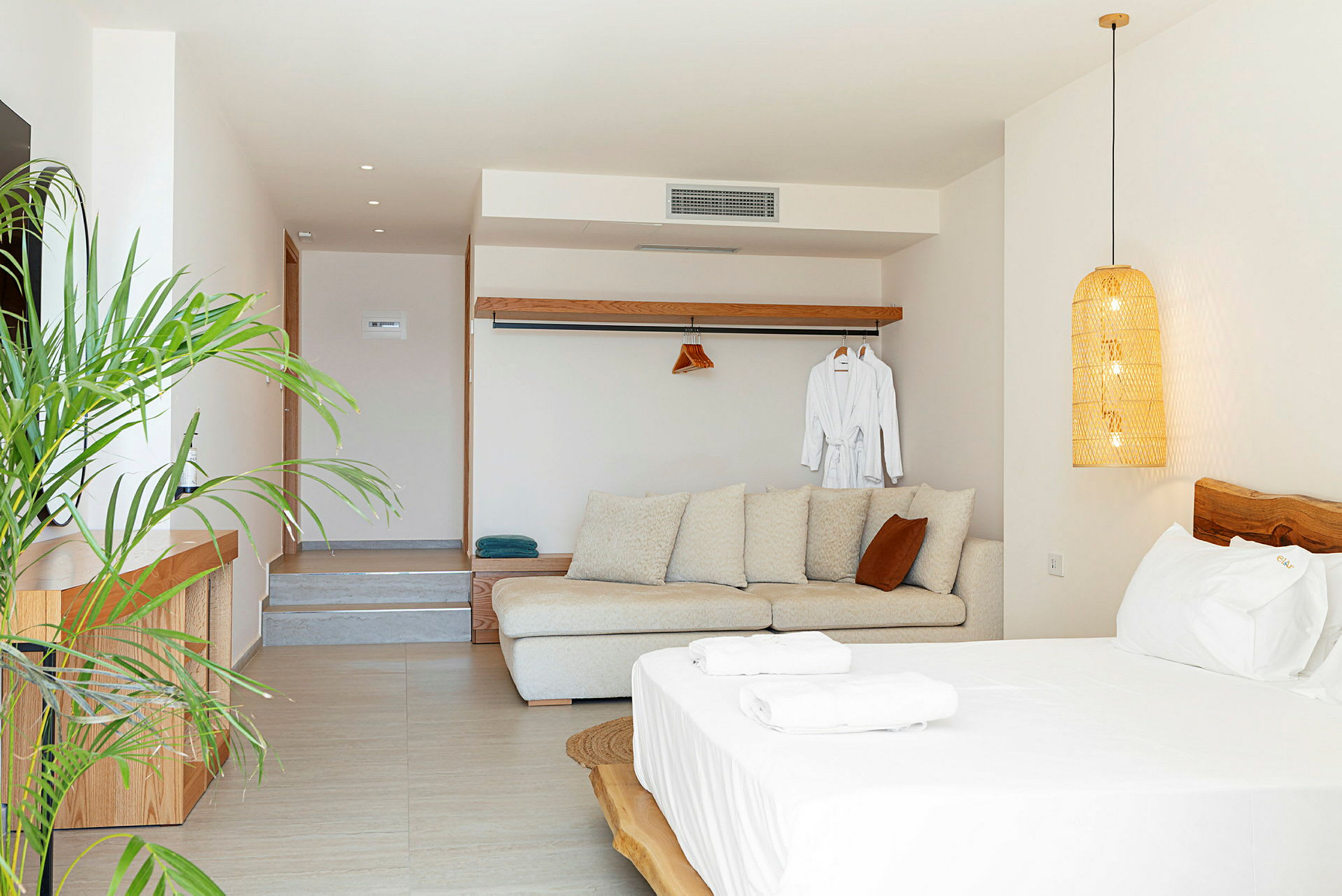 Et lyst og moderne hotelværelse med sofa, seng og planter. (AI-genereret tekst)