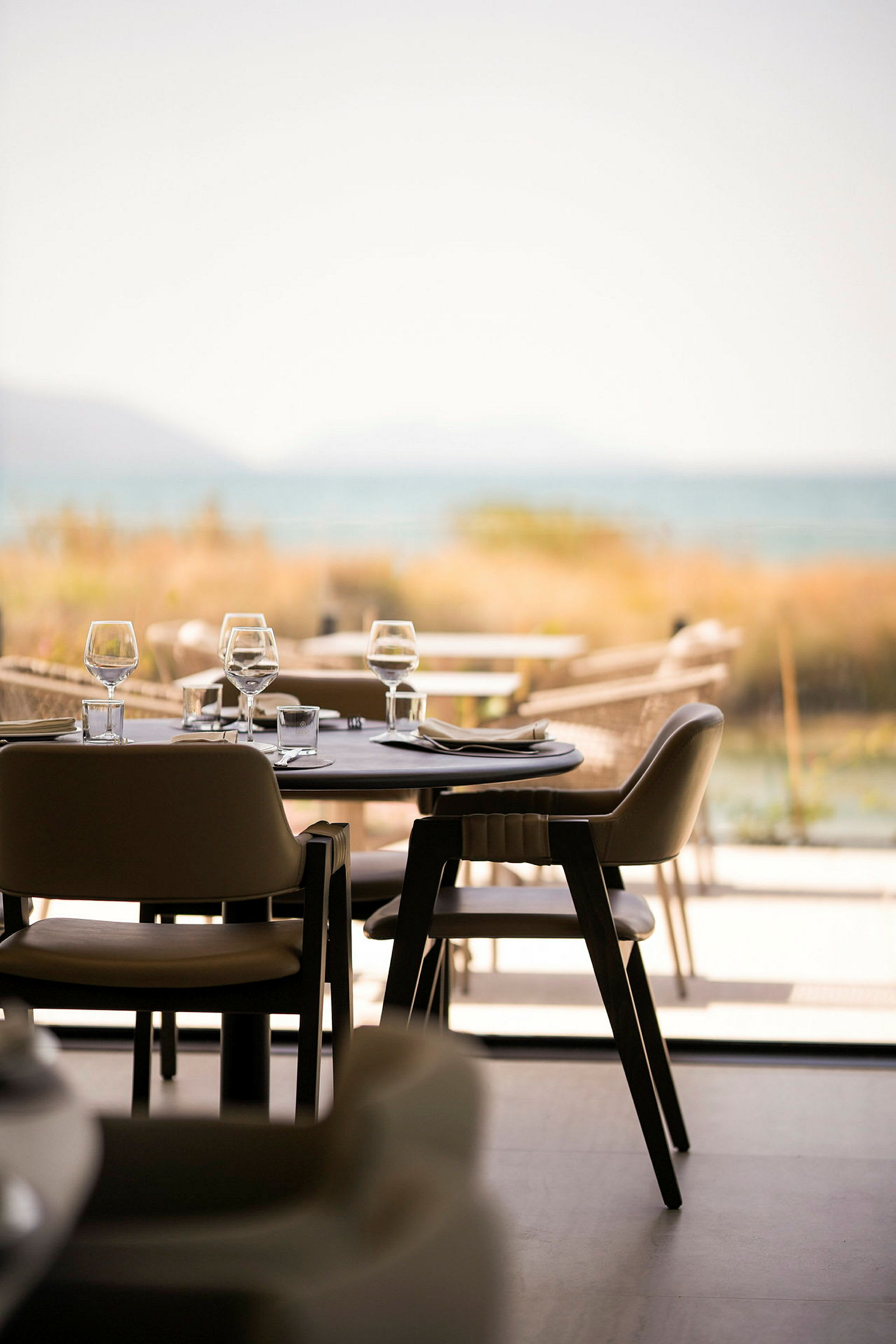 En elegant restaurant med dækkede borde og stole, med udsigt over havet. (AI-genereret tekst)