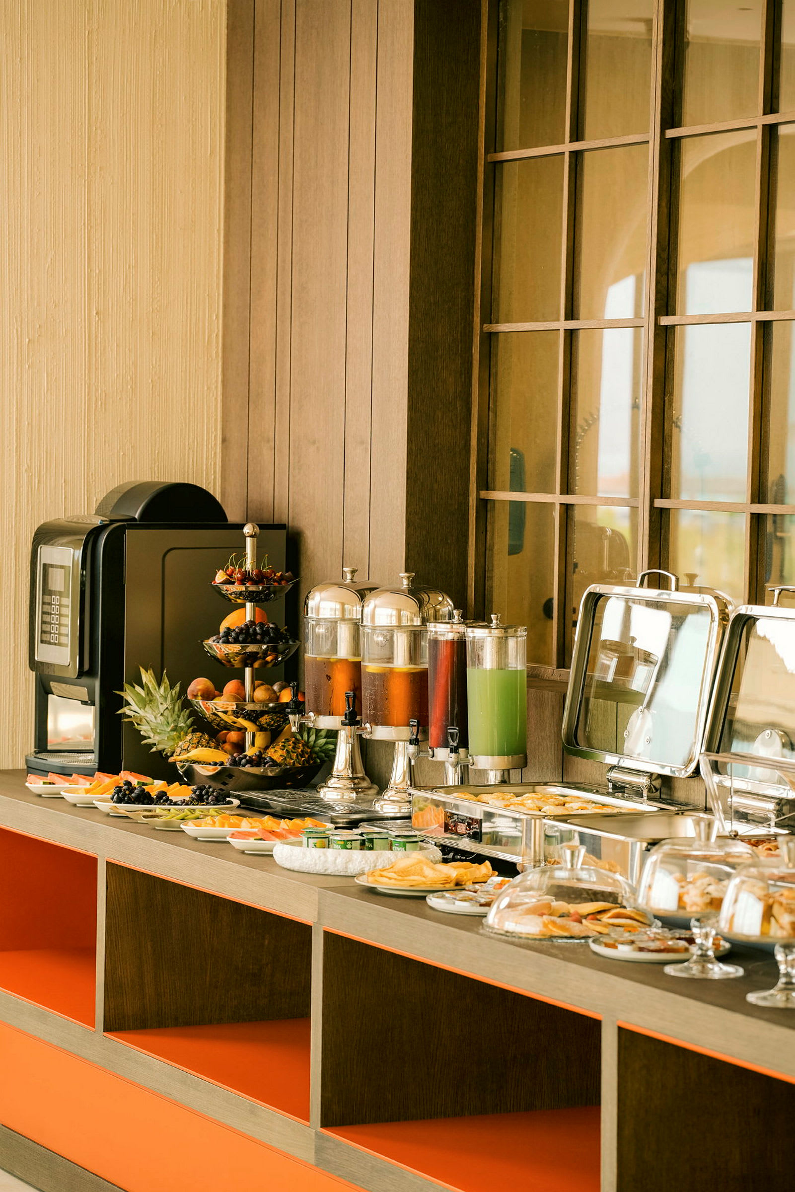 Et morgenmadbuffetbord med forskellige retter, frugter, juiceautomater og en kaffemaskine. (AI-genereret tekst)