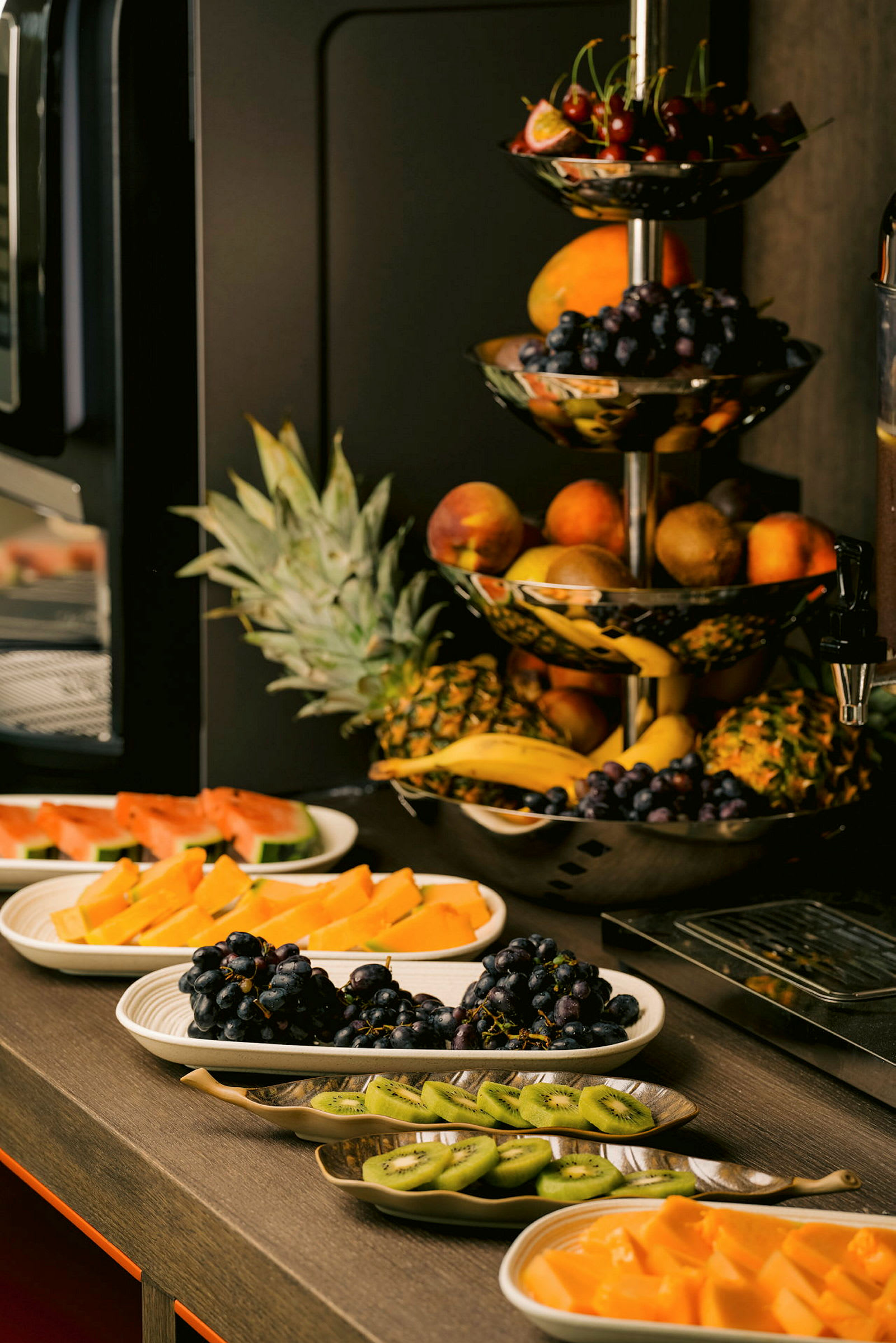 En buffetopsætning med forskellige friske frugter som druer, kiwi, vandmelon og ananas. (AI-genereret tekst)