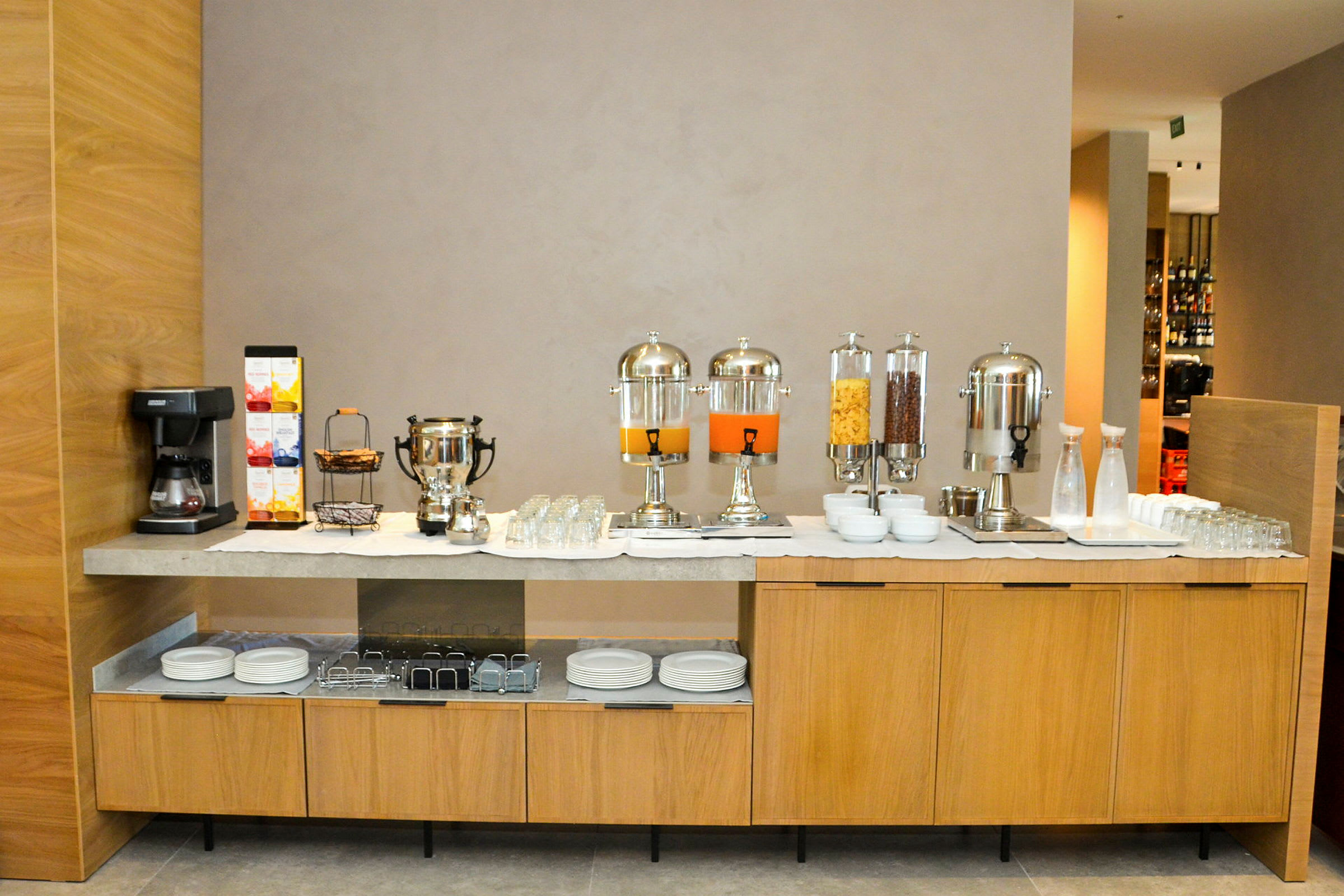 En morgenmadsbuffet med kaffemaskine, juicebeholdere og skåle med morgenmadsprodukter på en bordplade. (AI-genereret tekst)