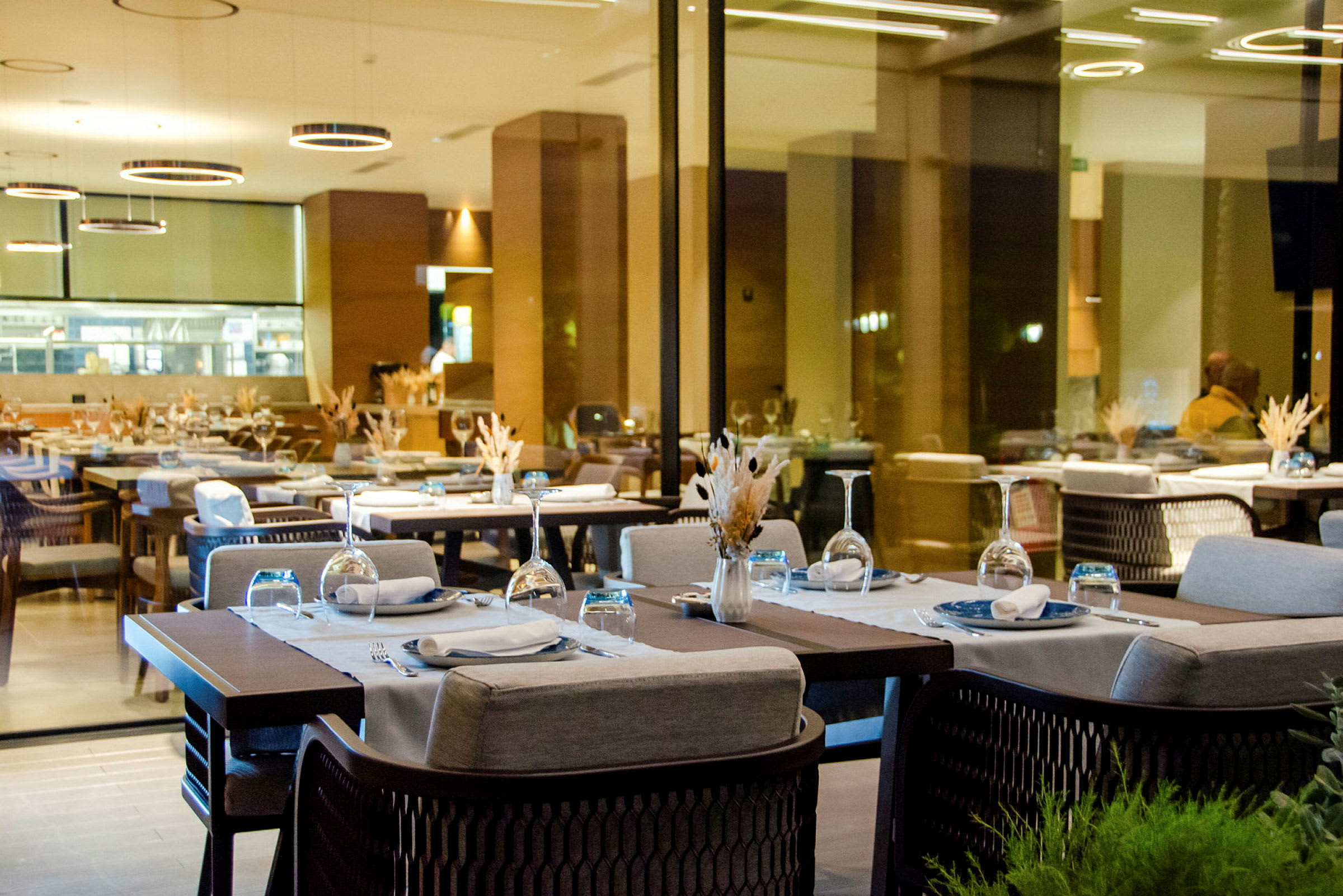 Billede af en moderne restaurant med dækkede borde og glasvægge. (AI-genereret tekst)