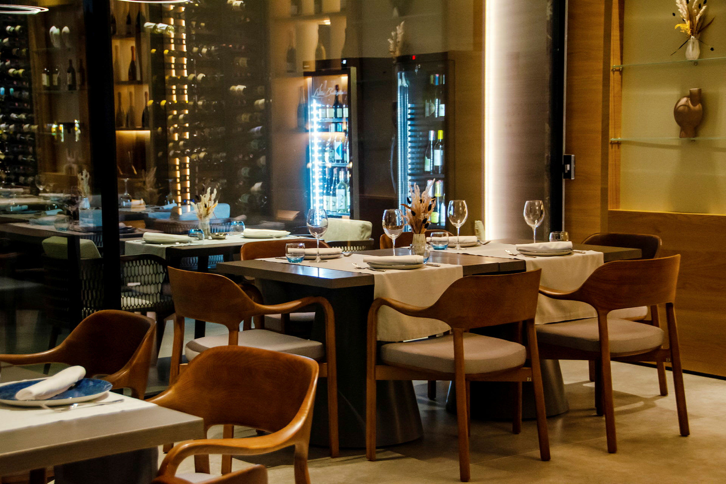 En elegant og moderne restaurant med opdækkede borde og vinopbevaring i baggrunden. (AI-genereret tekst)