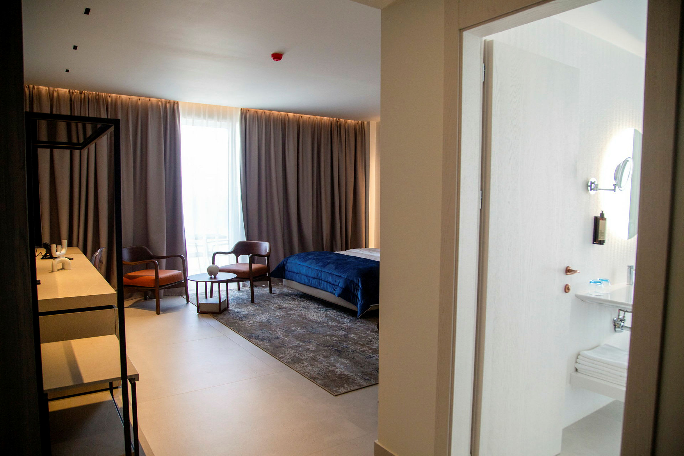 Hotelværelse med seng, siddeområde og skrivebord samt tilhørende badeværelse. (AI-genereret tekst)