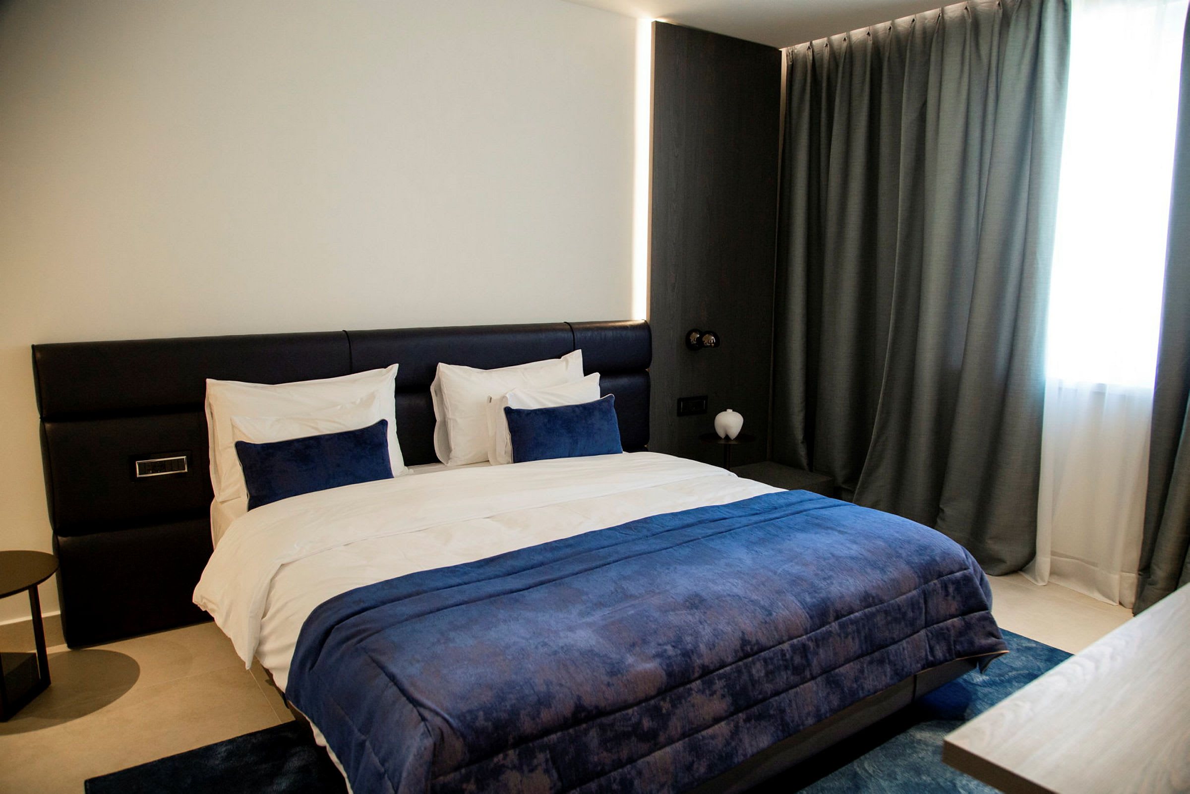 Et moderne hotelværelse med en stor seng med blå sengetøj. (AI-genereret tekst)