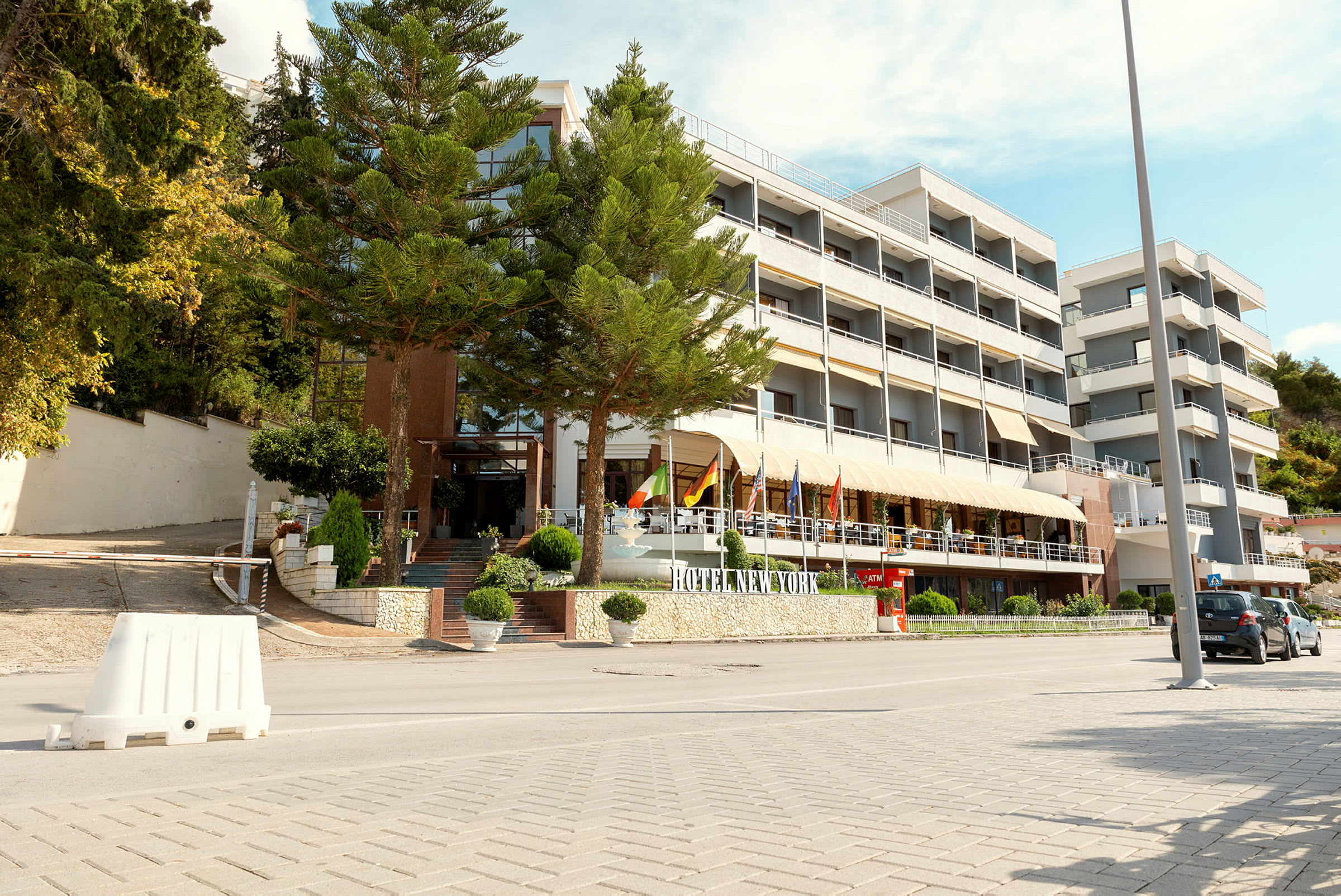 Hotel New York med flere etager og indgangsområde ved en vej. (AI-genereret tekst)
