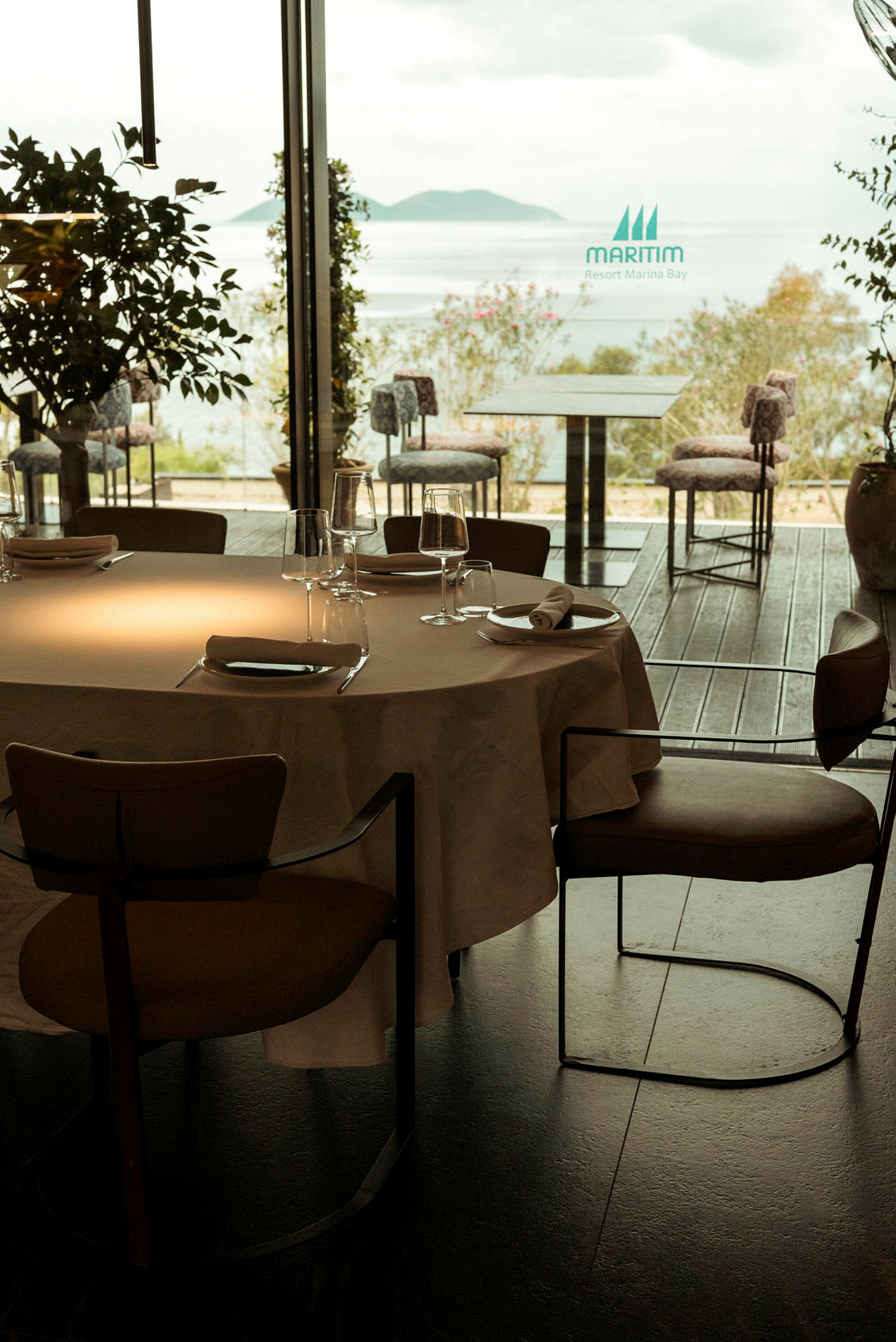 Et bord med dug og glas på en restaurant med udsigt over havet. (AI-genereret tekst)