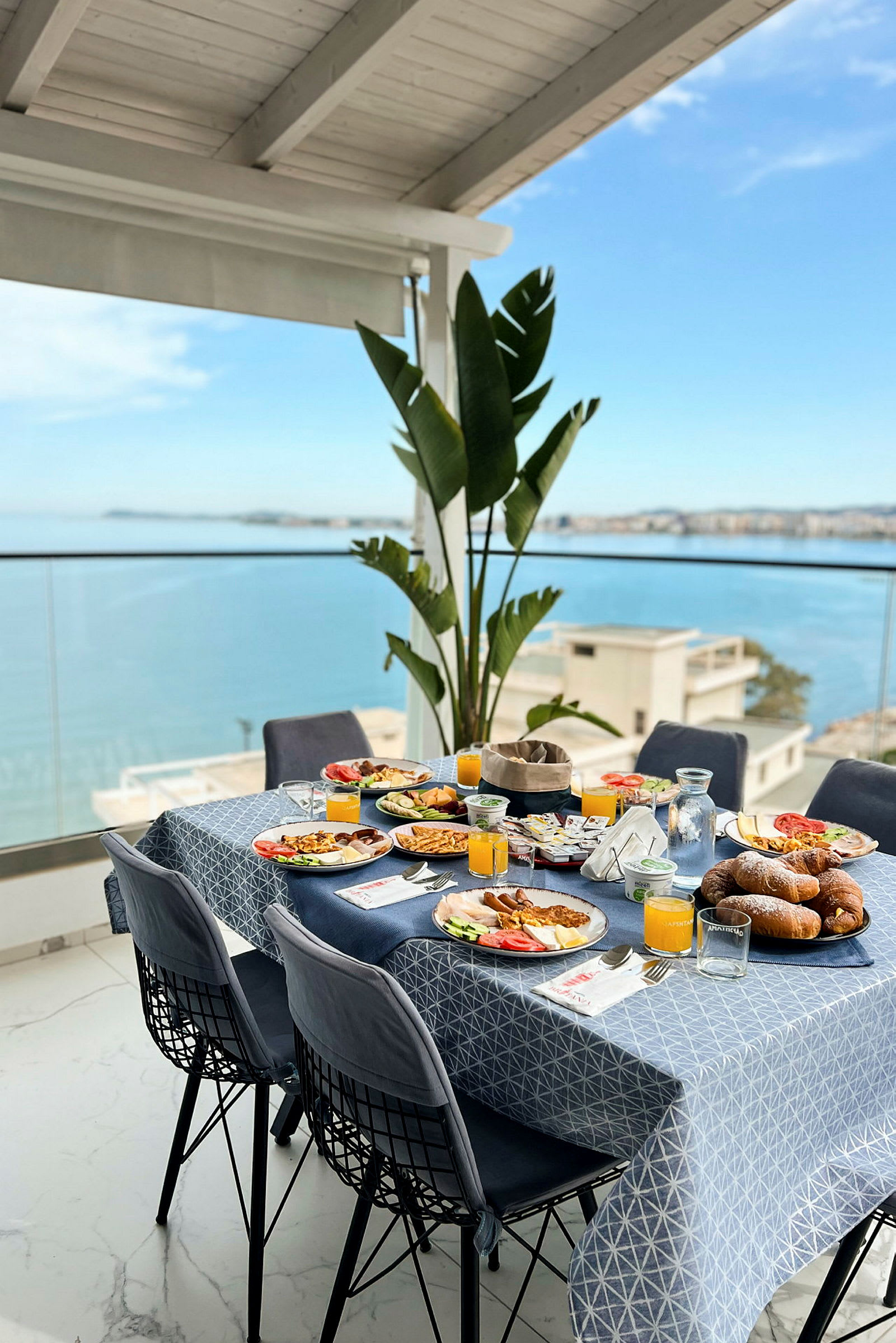 Et dækket bord med morgenmad på en terrasse med udsigt over havet. (AI-genereret tekst)