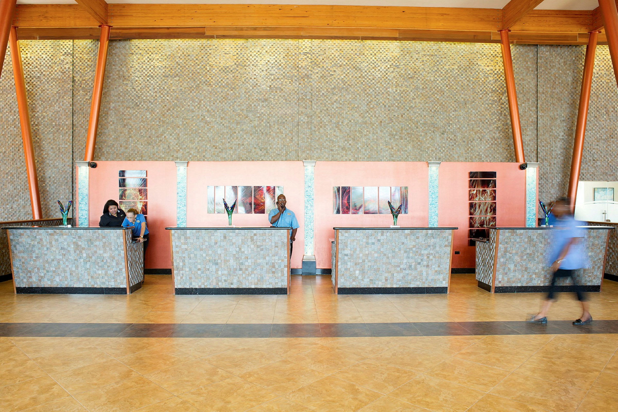 En reception med flere servicediske og dekorative blomster. Væggene har et skiftende mosaikdesign. (AI-genereret tekst)