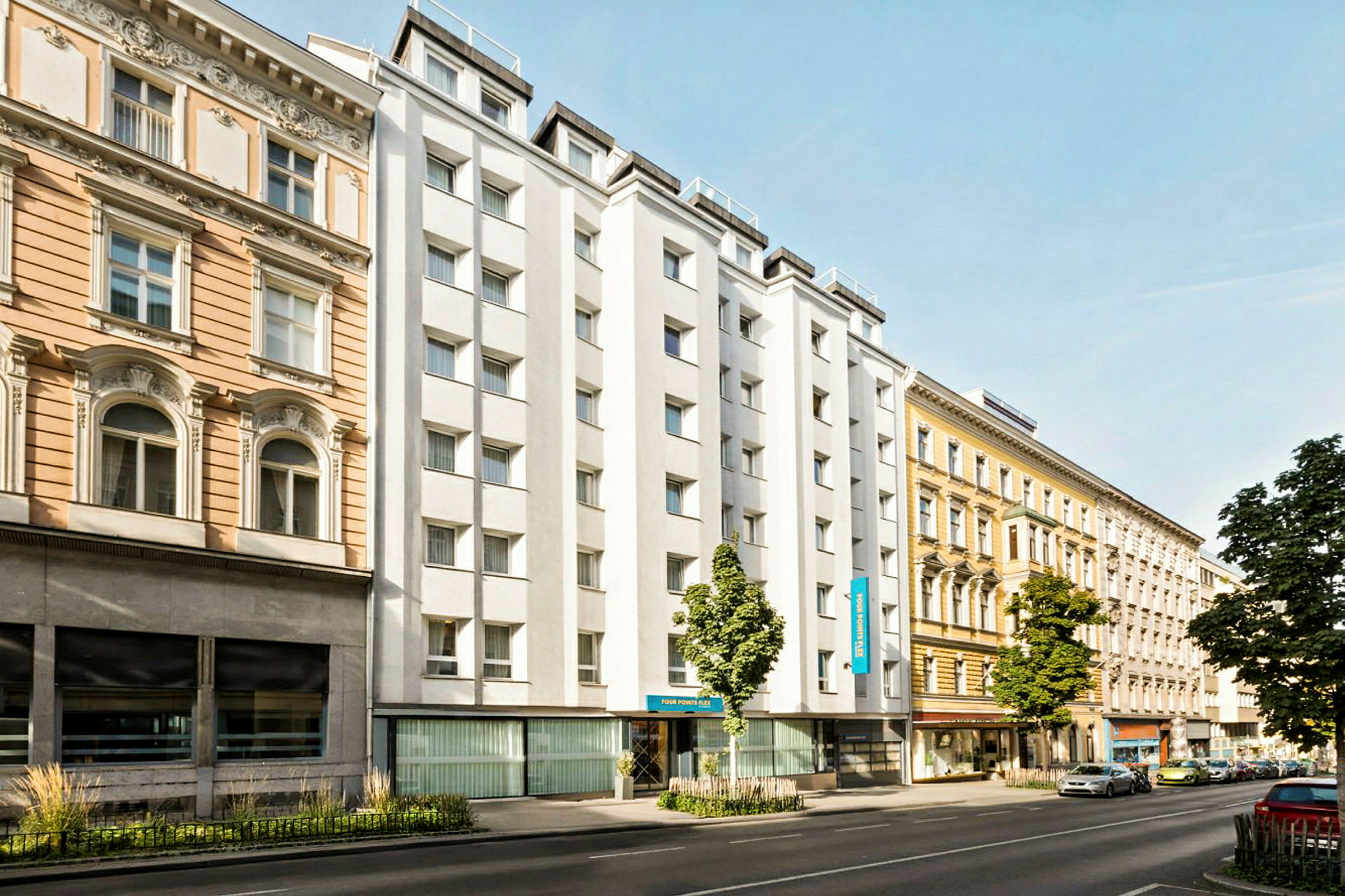 En byvej med bygninger fra forskellige årtier, herunder et hotel med en hvid facade. (AI-genereret tekst)